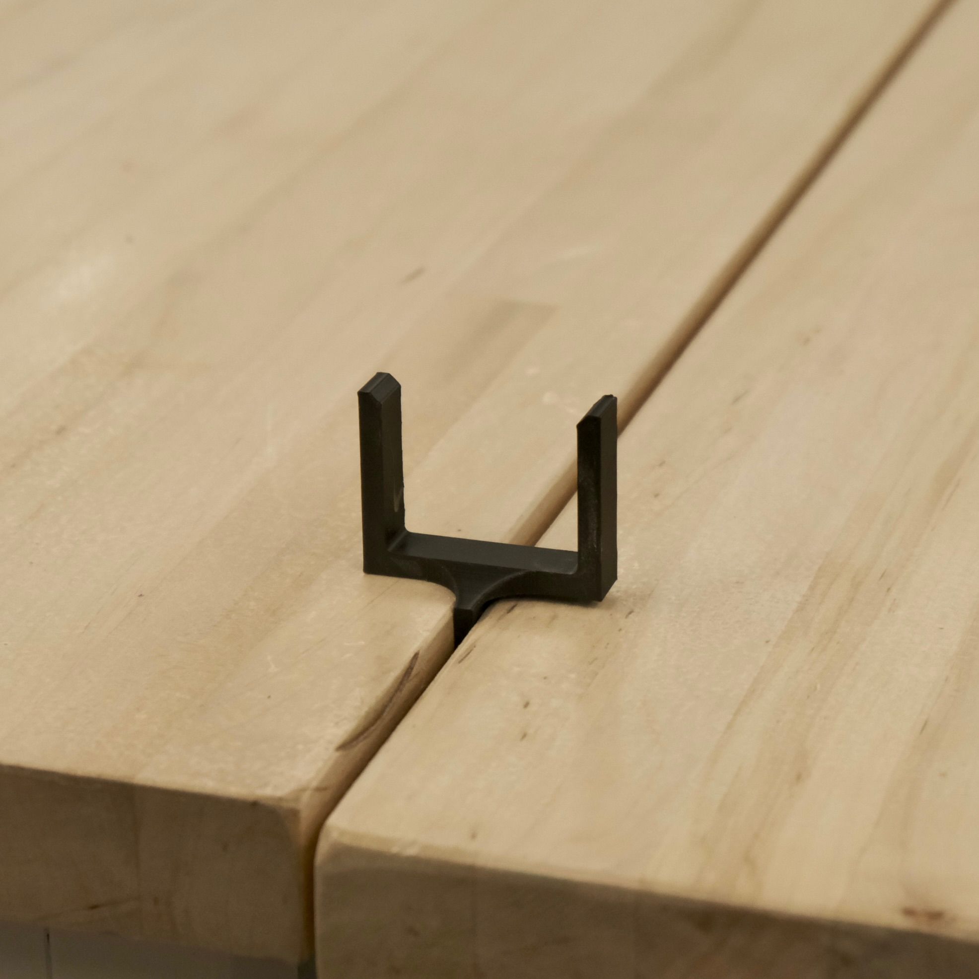 black plastic clip with the stem inserted between two wooden tables