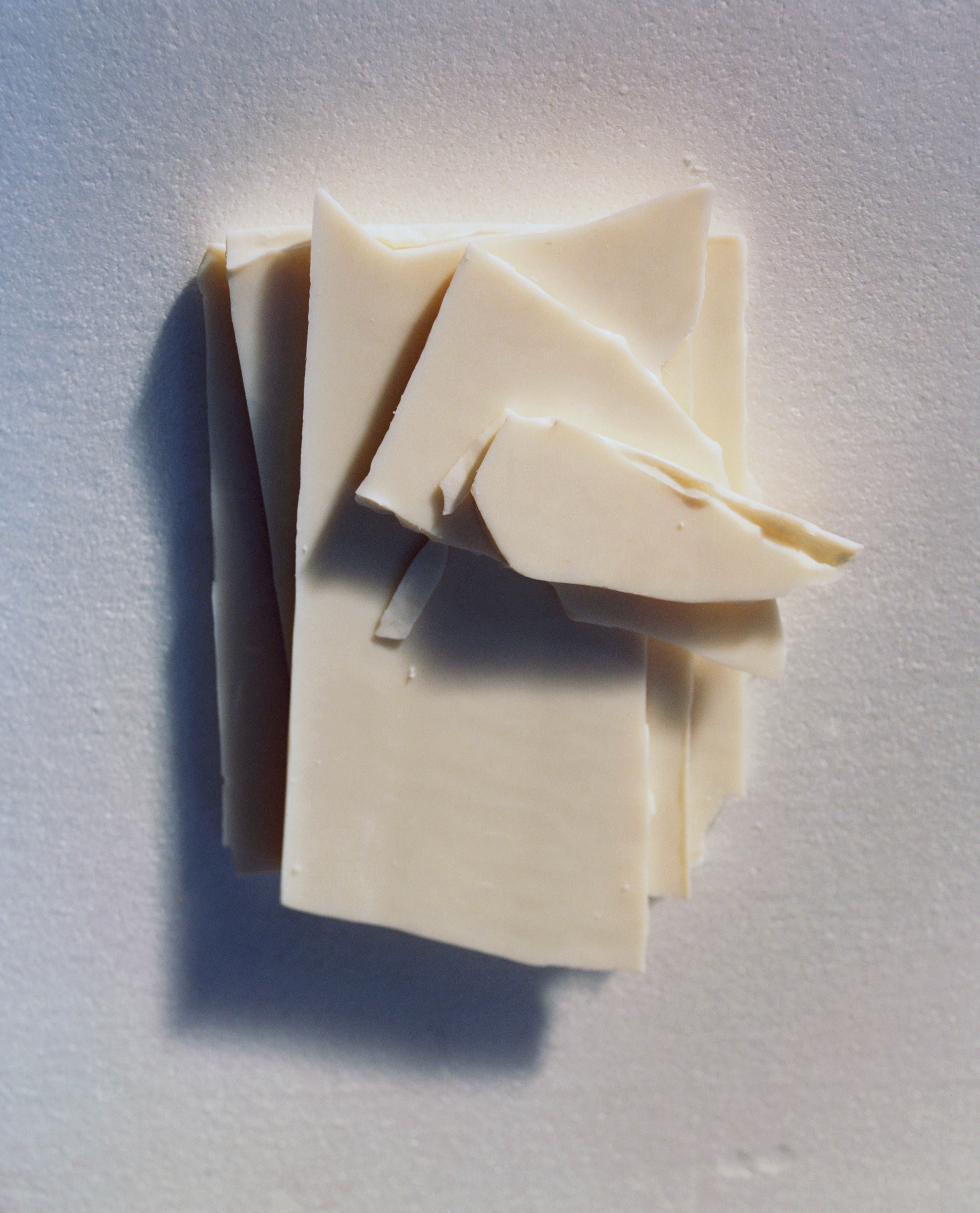 Stack of thin ivory shards arranged on a softly dusted surface, lit to cast gentle shadows.