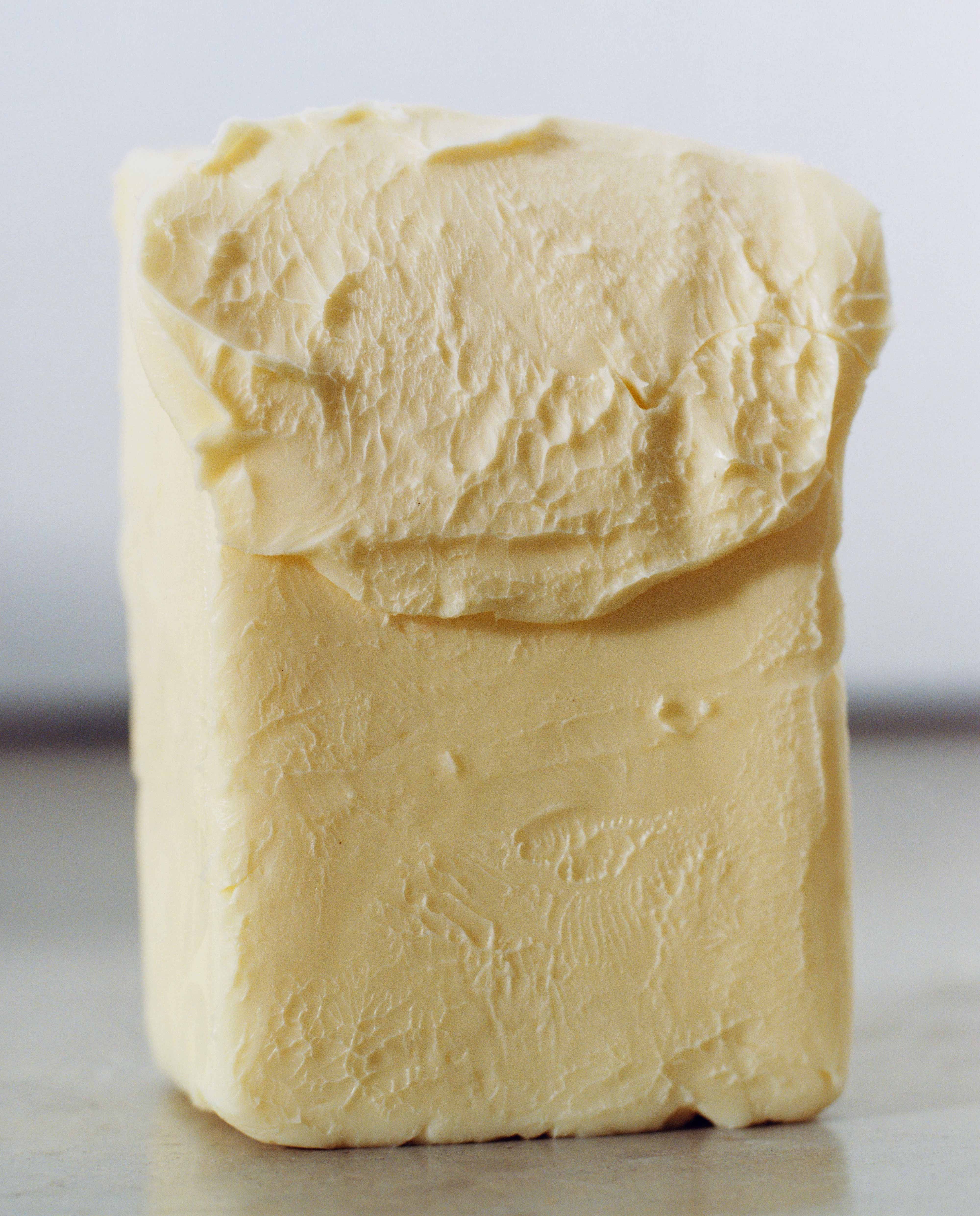 Close-up of a cream-colored rectangular butter with a textured, folded top, set on a neutral surface.