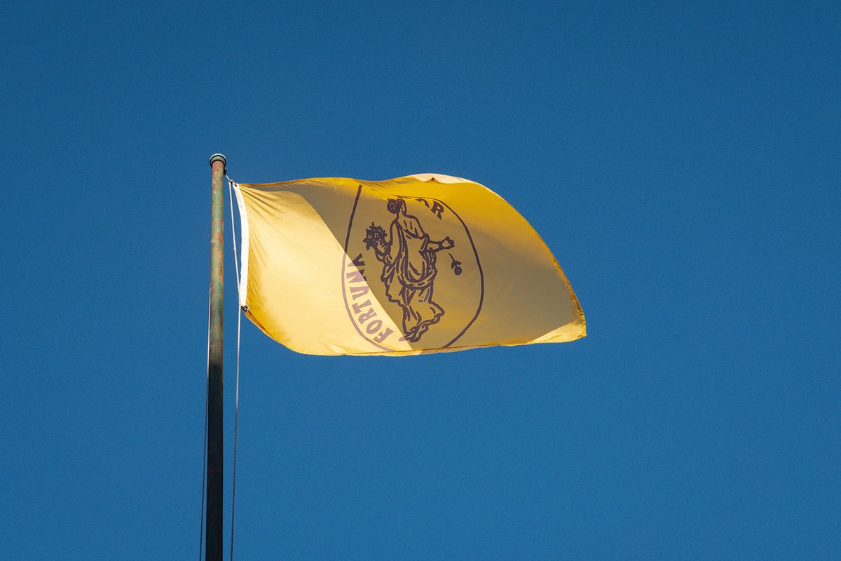 Bar Fortuna's yellow flag, featuring the namesake Roman goddess, flapping against a clear blue sky