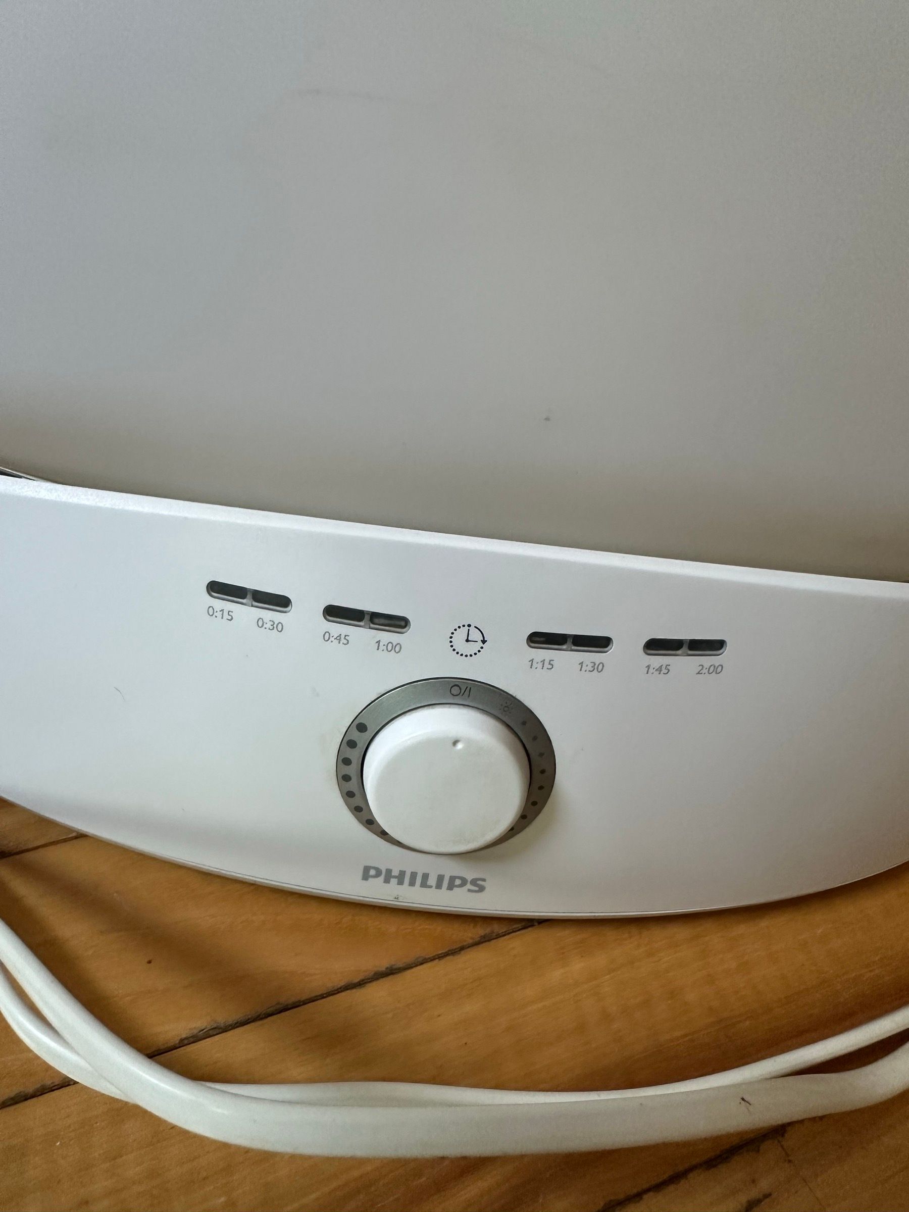 Large white Philips full-spectrum light therapy lamp with a timer dial and power cord.