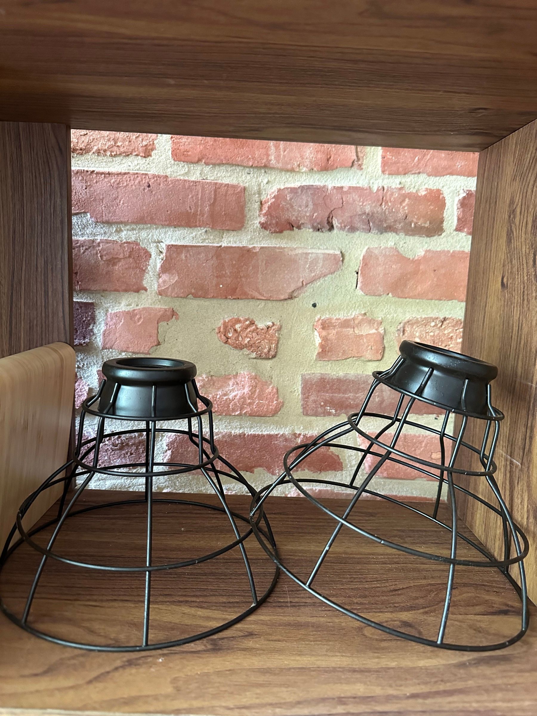 A pair of black wire cage pendant light shades, with a tape measure showing about 8-9 inches across.