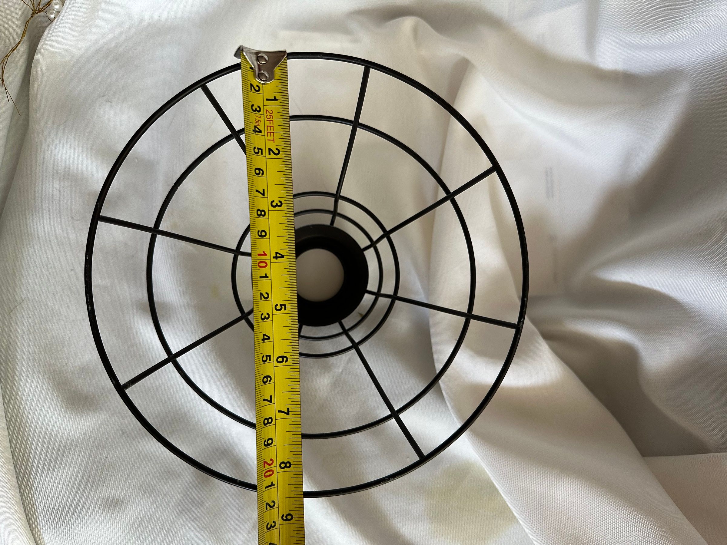 A pair of black wire cage pendant light shades, with a tape measure showing about 8-9 inches across.