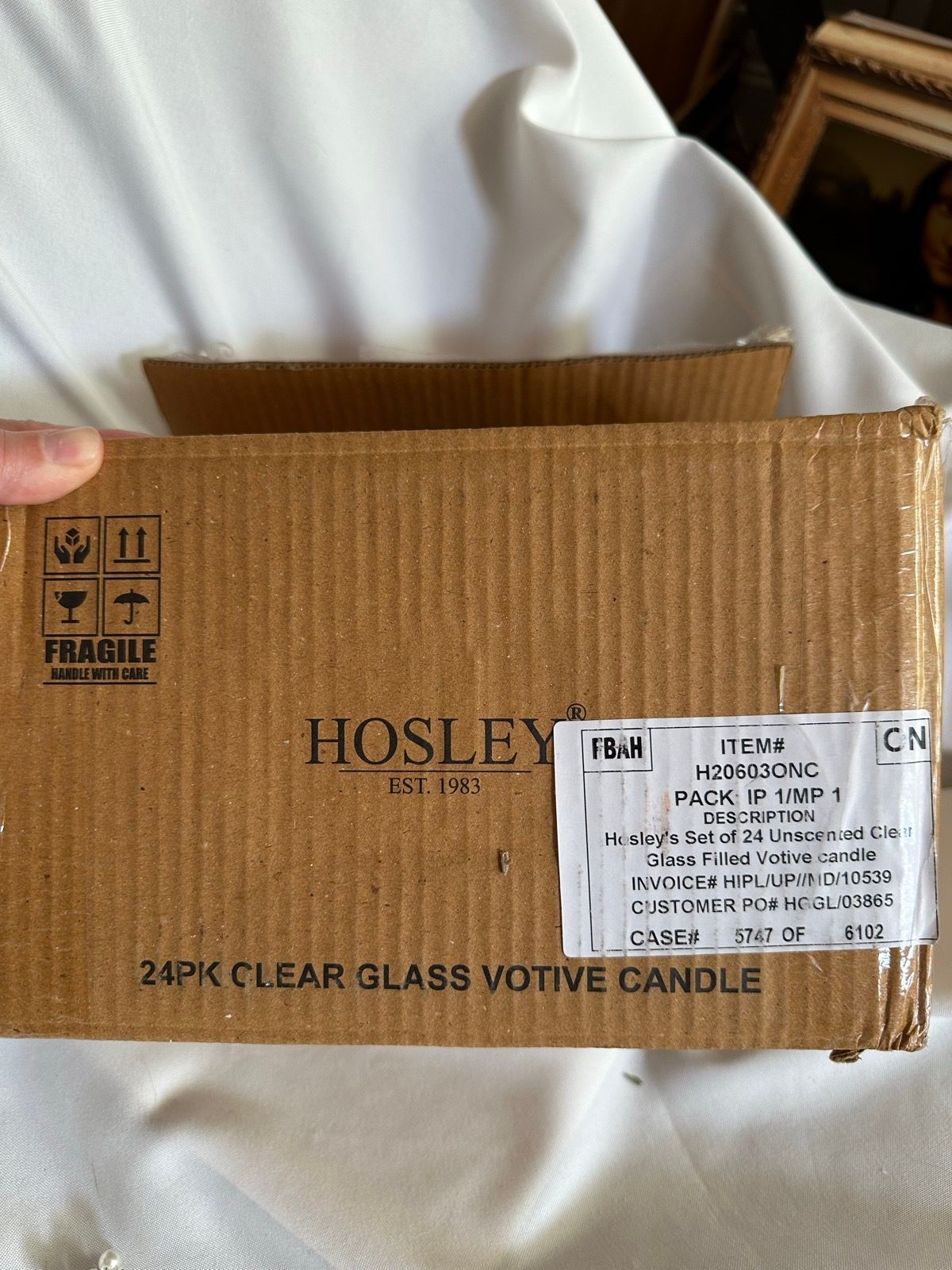 A box of Hosley clear glass votive candles.