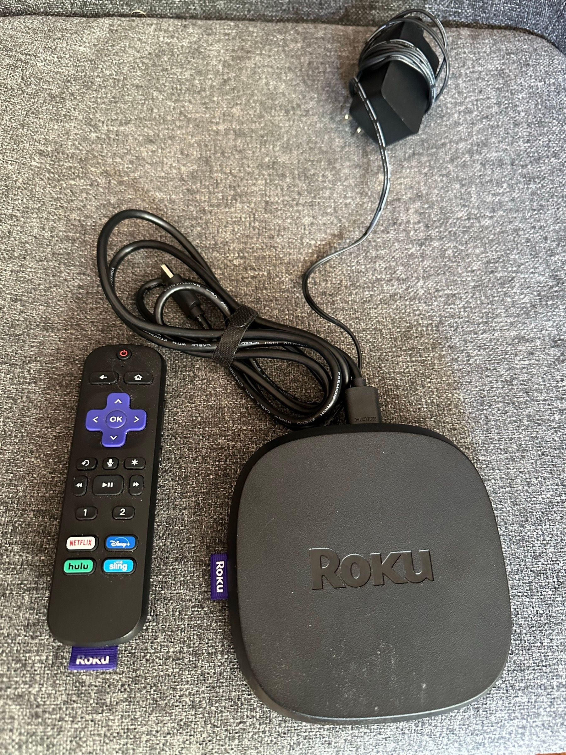 Roku Ultra streaming box with its voice remote, HDMI cable, and power adapter.