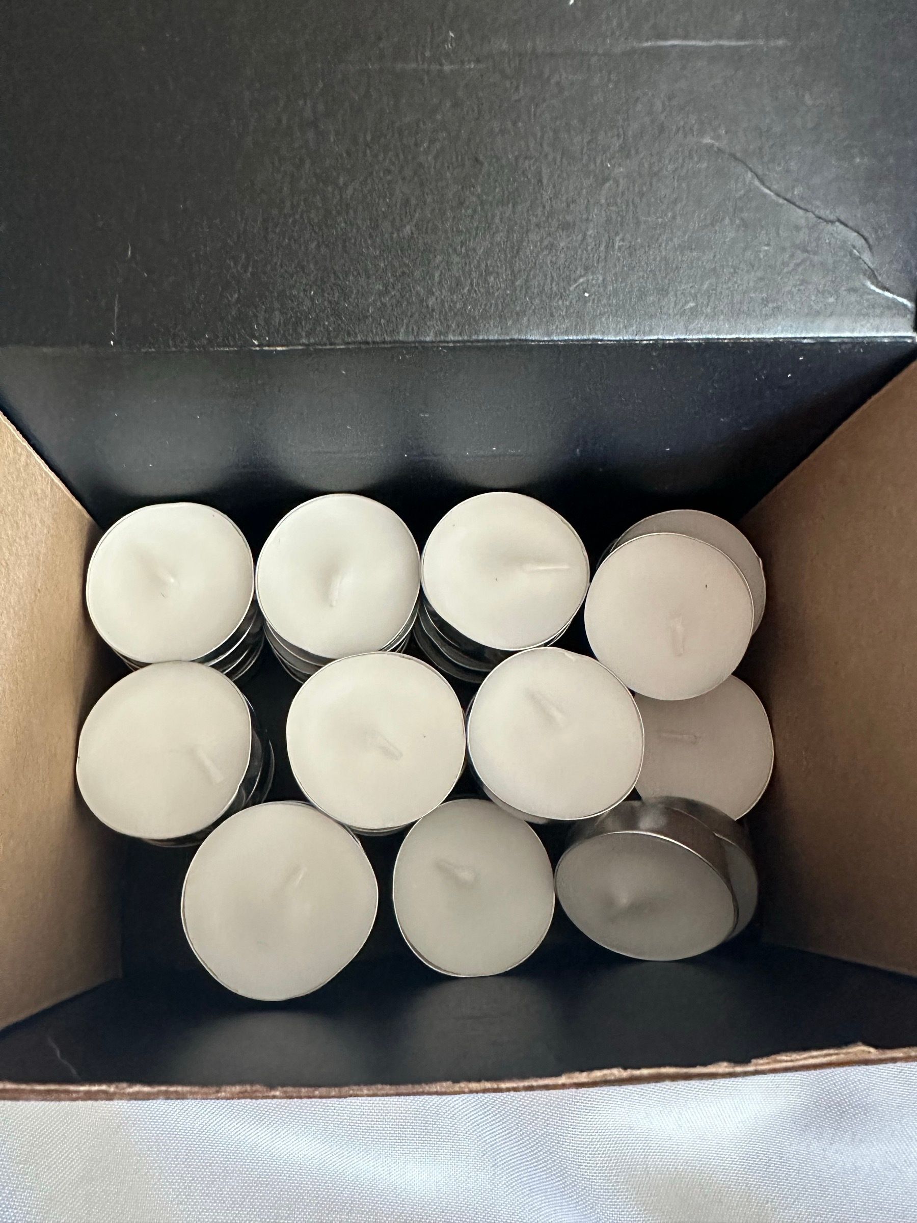 A boxful of white unscented tea light candles.