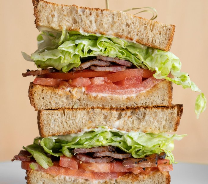 Stacked BLT sandwich with bacon, lettuce, tomato and house-made seed bread