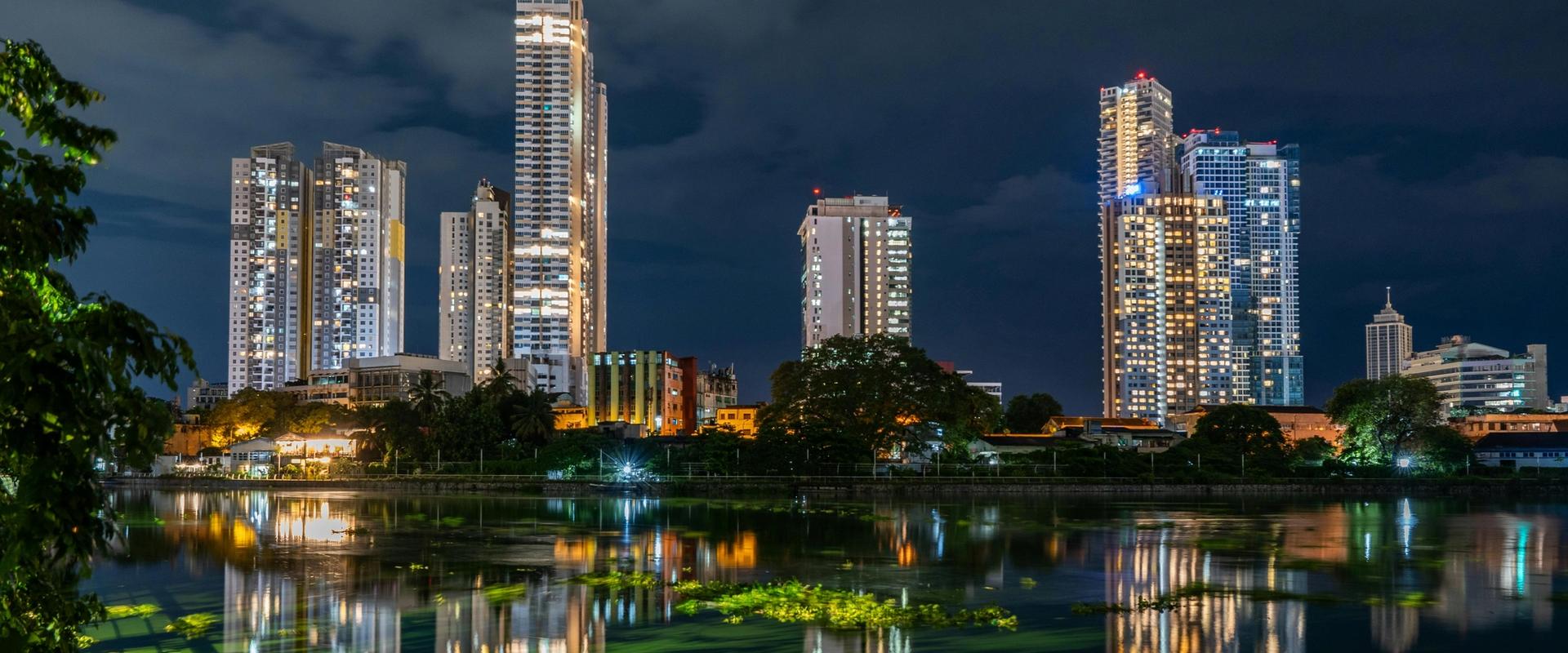 Colombo city skyline at night with modern skyscrapers reflected in Beira Lake, Sri Lanka