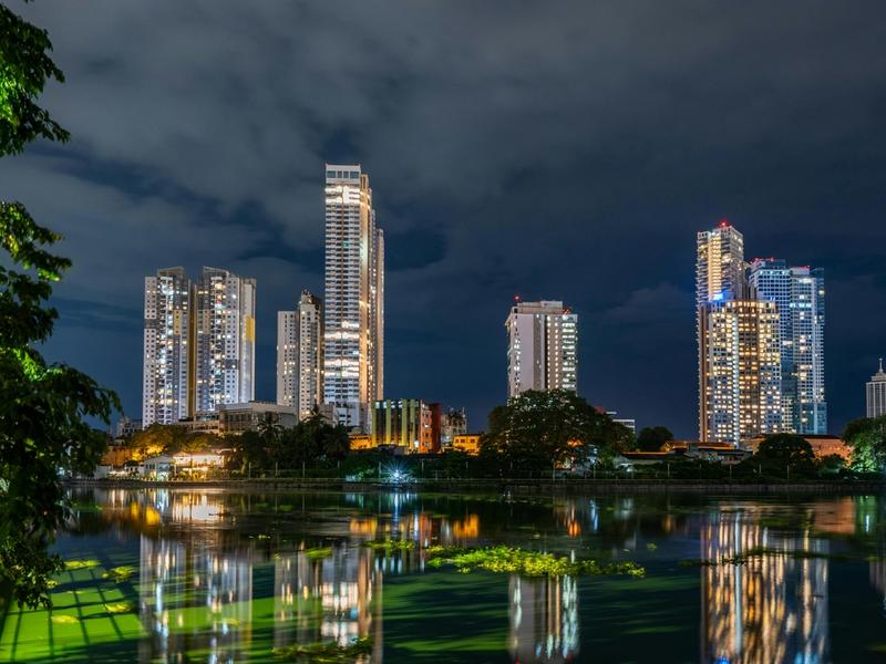 Colombo city skyline at night with modern skyscrapers reflected in Beira Lake, Sri Lanka