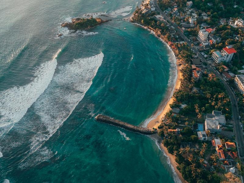 Aerial view of Mirissa beach and coastline with turquoise waves at sunset, Sri Lanka