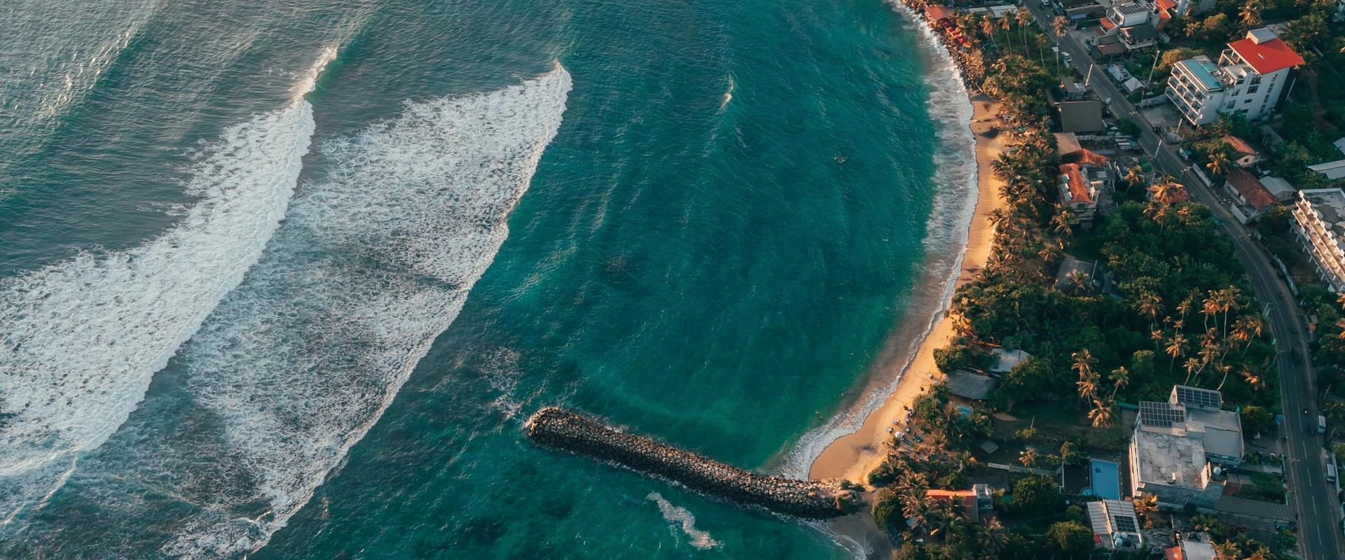 Aerial view of Mirissa beach and coastline with turquoise waves at sunset, Sri Lanka