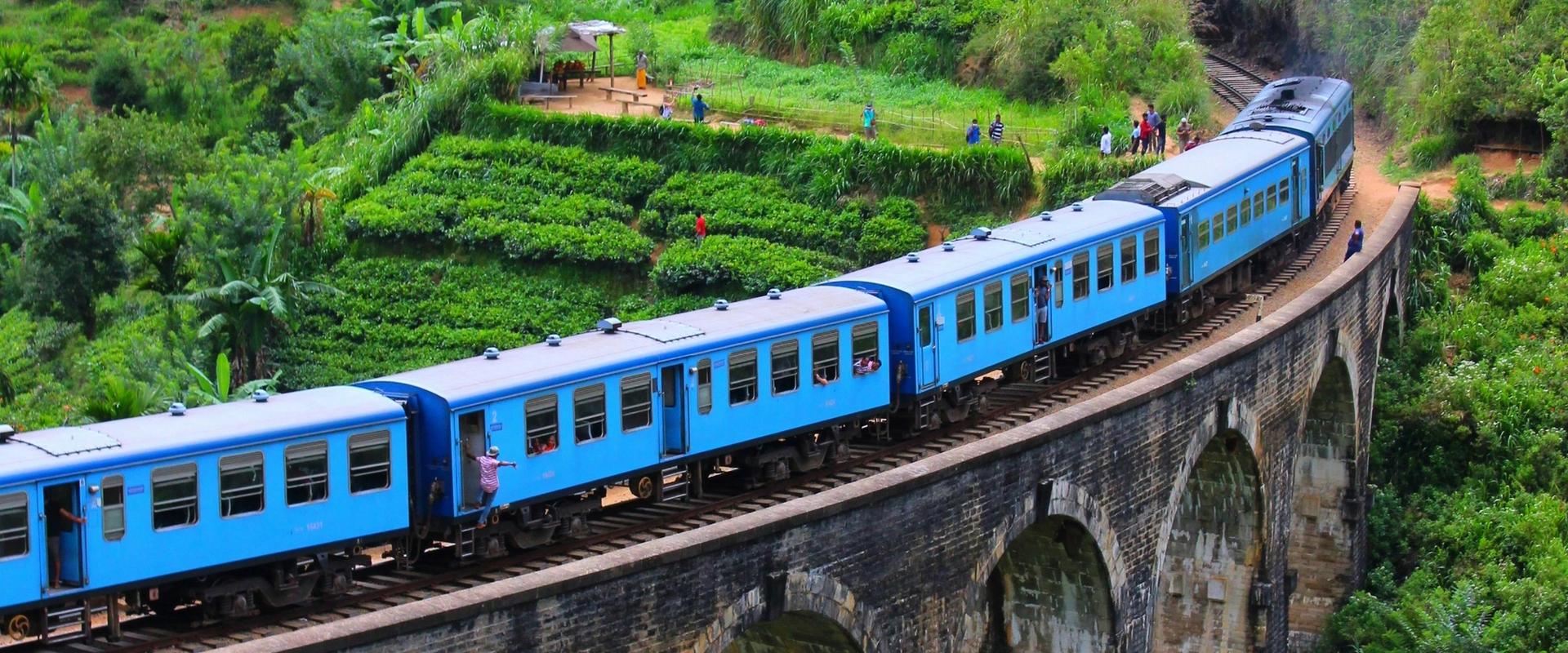 Blue train crossing the Nine Arches Bridge in Ella, Sri Lanka surrounded by lush green tea plantations