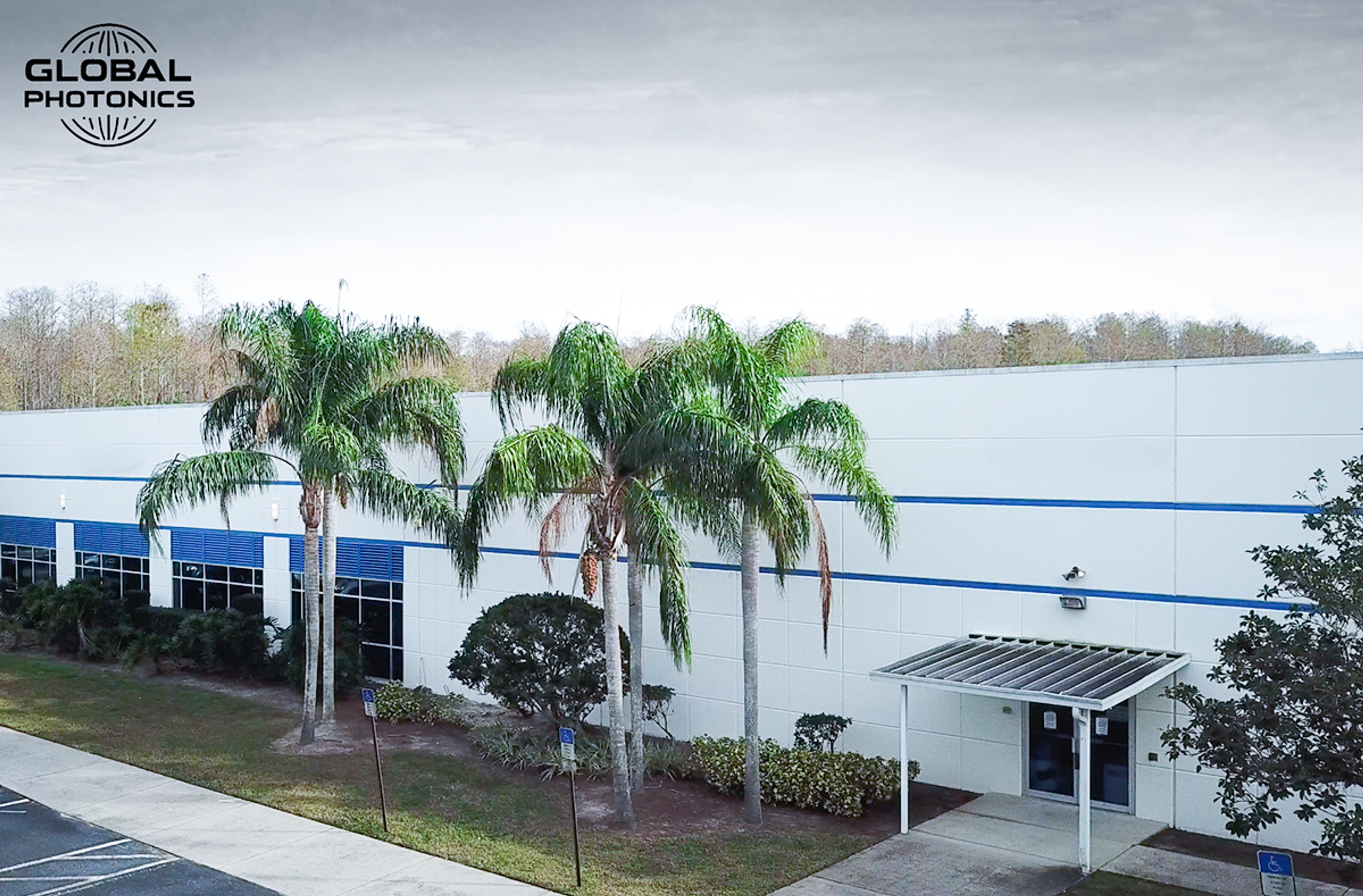 New G&H Tampa building in Florida, white external facade with blue stripe and window shutter, palm trees to from car park
