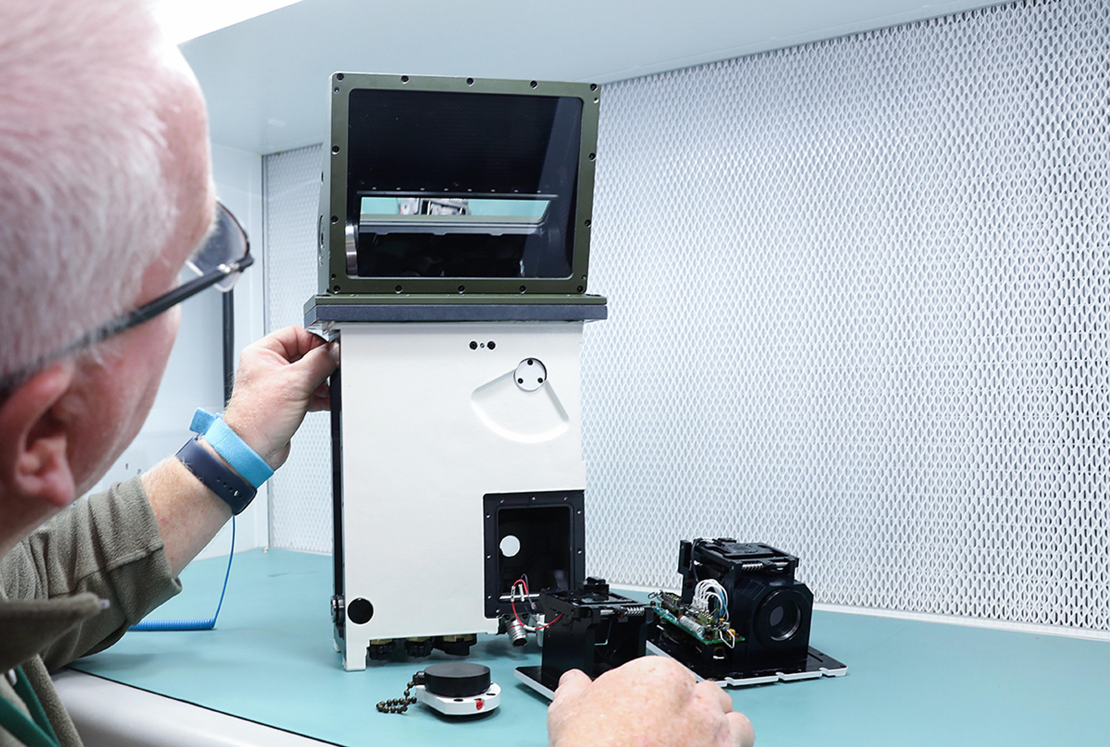 G&H technician inspecting and assembling an optical vision system during quality control at the St Asaph Optical Systems Innovation Hub.