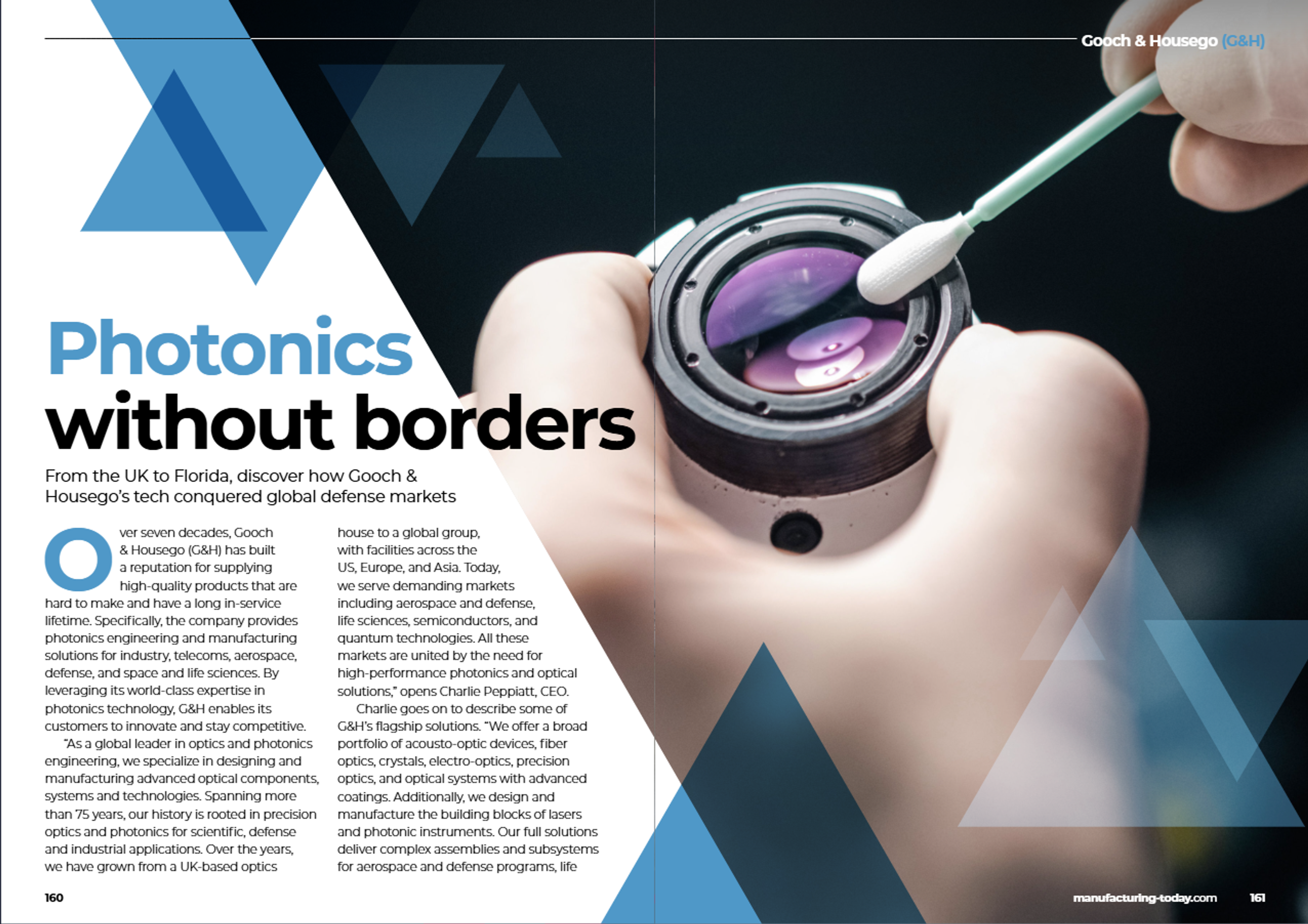 A double-page magazine spread from Manufacturing Today featuring an article titled "Photonics without borders." The left page shows the title in large blue and black text with a subheading: "From the UK to Florida, discover how Gooch & Housego’s tech conquered global defense markets." Below, the article describes G&H’s history, capabilities in photonics and defense, and global manufacturing footprint. The background includes abstract blue triangle graphics. The right page displays a close-up image of a gloved hand using a swab to clean an optical lens with purple coatings, emphasizing precision and cleanliness. The Gooch & Housego (G&H) logo is in the top-right corner.