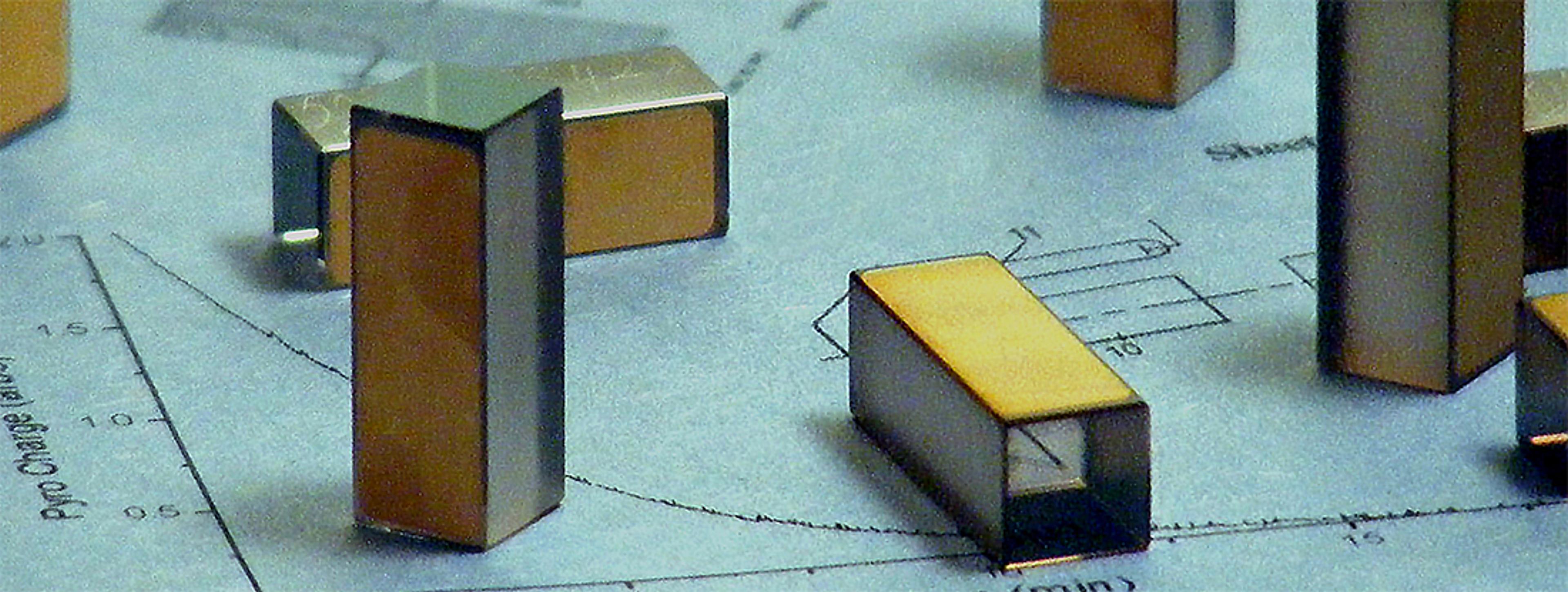 Lithium Niobate Q-Switches product image - Multiple precision optical components, resembling rectangular Q-switch crystals, are shown standing and lying on a technical drawing. Each unit features clear polished sides with a gold-coated surface, indicating their use in high-performance laser systems or photonics equipment. The background includes engineering sketches and measurement curves, emphasizing a laboratory or manufacturing setting.