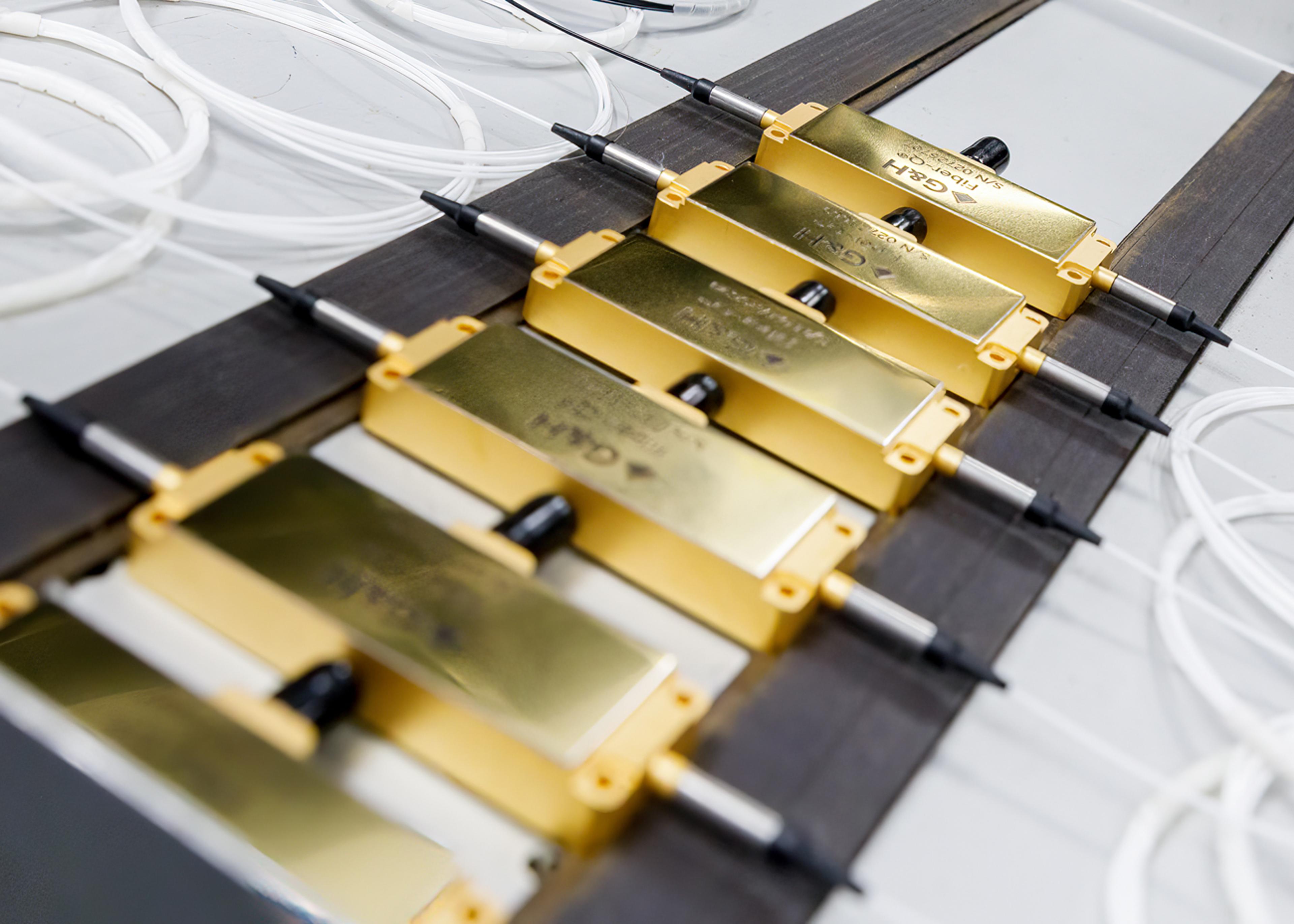 Tray of gold fibre-optic G&H Fiber-Q® modules with connectorised leads and coiled white fibres arranged for inspection or testing.