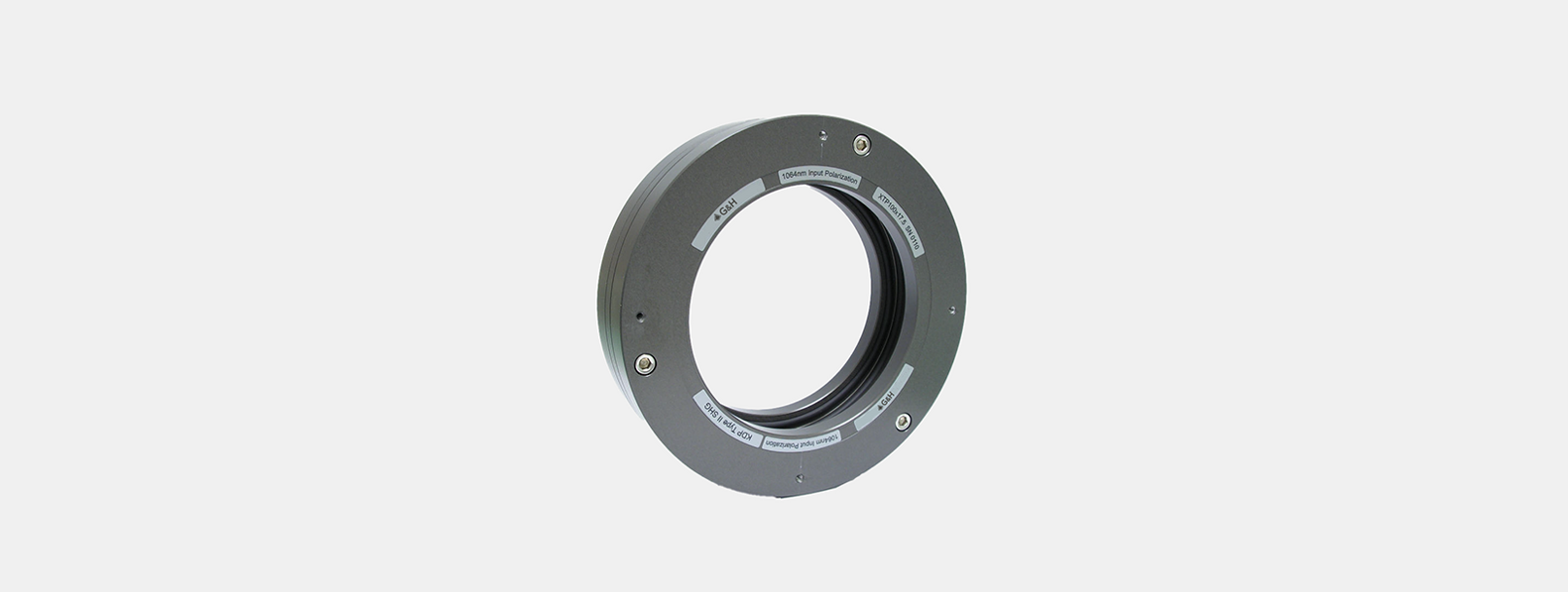 XTP Nonlinear Crystal Holder product image - A circular G&H optical component with a central aperture, designed as a crystal holder. The device is constructed from a metallic material and features engraved labels around its circumference indicating alignment details such as "1064nm Input Polarization," "RTP Thin SHG," and "Return Input Polarization." The ring includes visible screws for securing the assembly and precise positioning, suggesting use in laser or photonic systems.