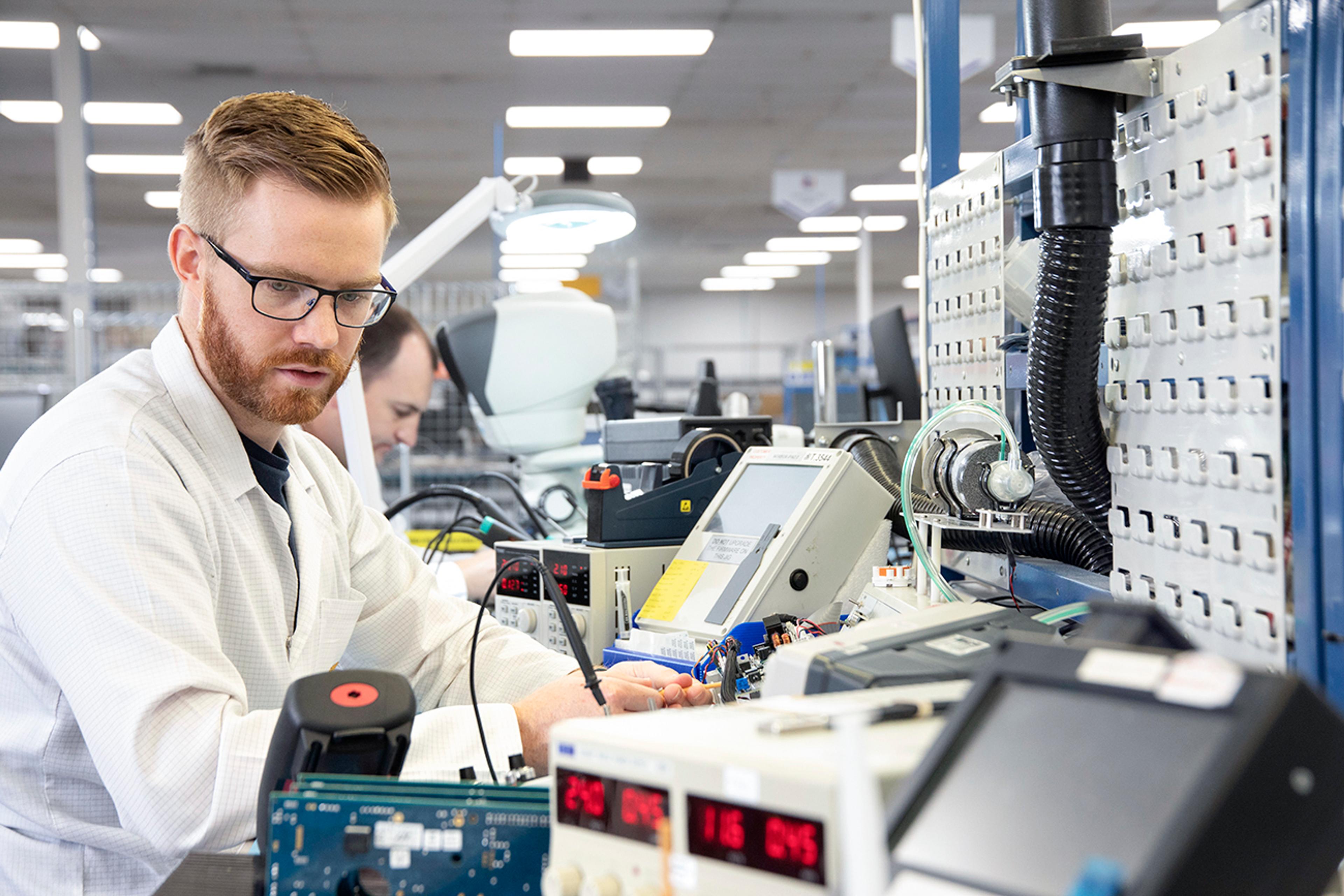 G&H engineer performing verification manufacturing, testing and calibrating electronic and photonics components on a production bench in a controlled manufacturing environment.