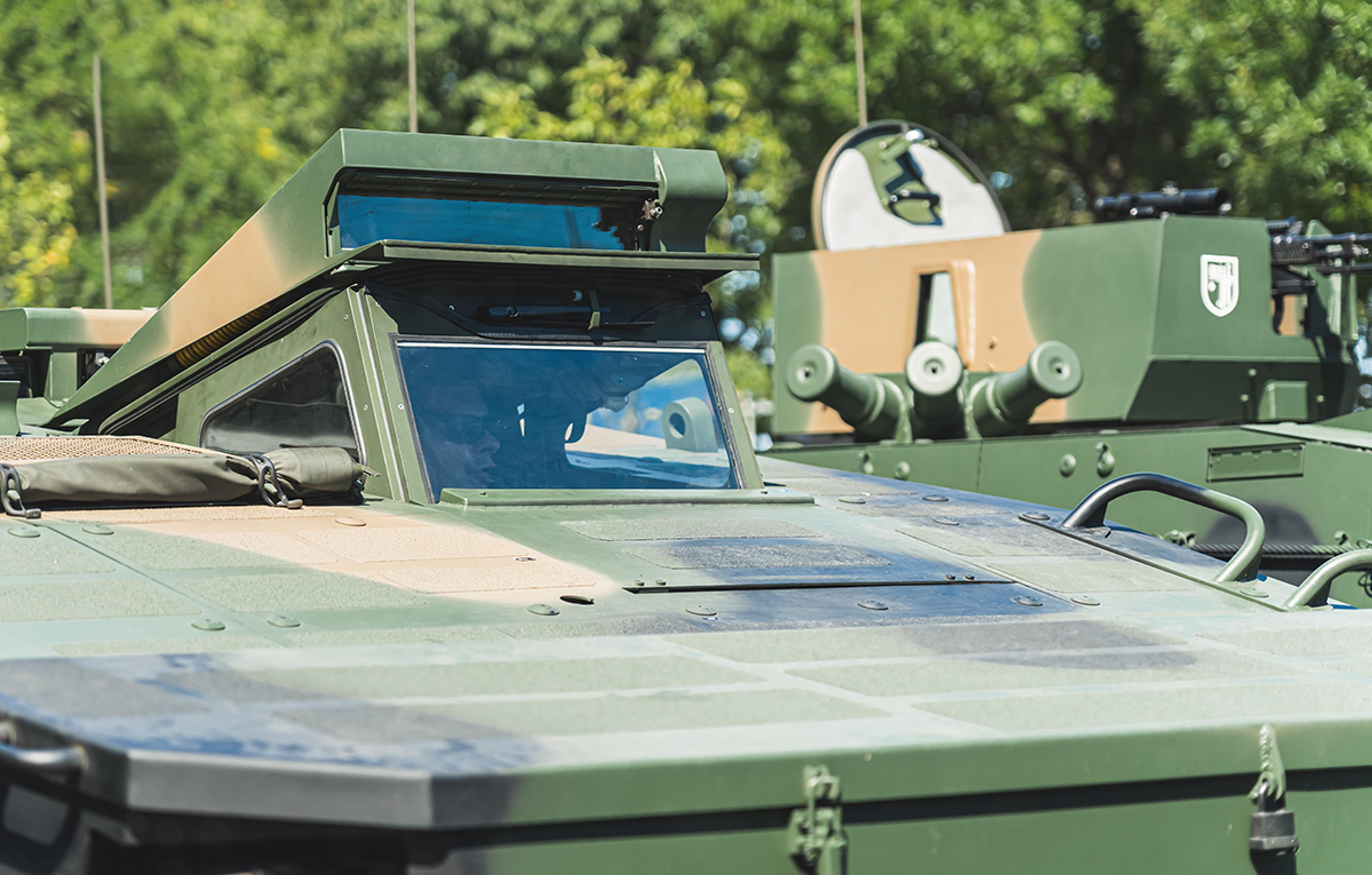 Close-up of an armoured military vehicle fitted with an elevated vision or periscope module above the driver’s position, with a turret visible behind it. The image highlights rugged integrated vehicle optics designed to support driver visibility, situational awareness, and protected mobility operations in defence environments.