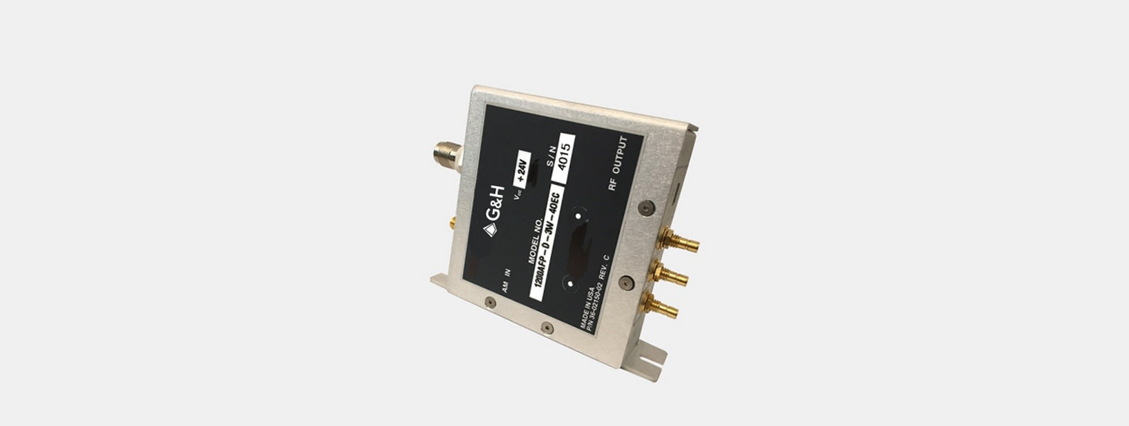 3910 series RF drivers product image - A G&H RF driver module (model 120AMP-D-3W-40EC) in a vertical orientation, housed in a silver metal casing with a black label plate. The label displays technical details including input voltage (+24V), model number, and serial number 4015. The unit features multiple gold-plated coaxial RF connectors on one side for RF output and auxiliary connections, and an SMA connector on the opposite side for input. The device is marked "Made in USA" with part number 36-02150-02 Rev. C.
