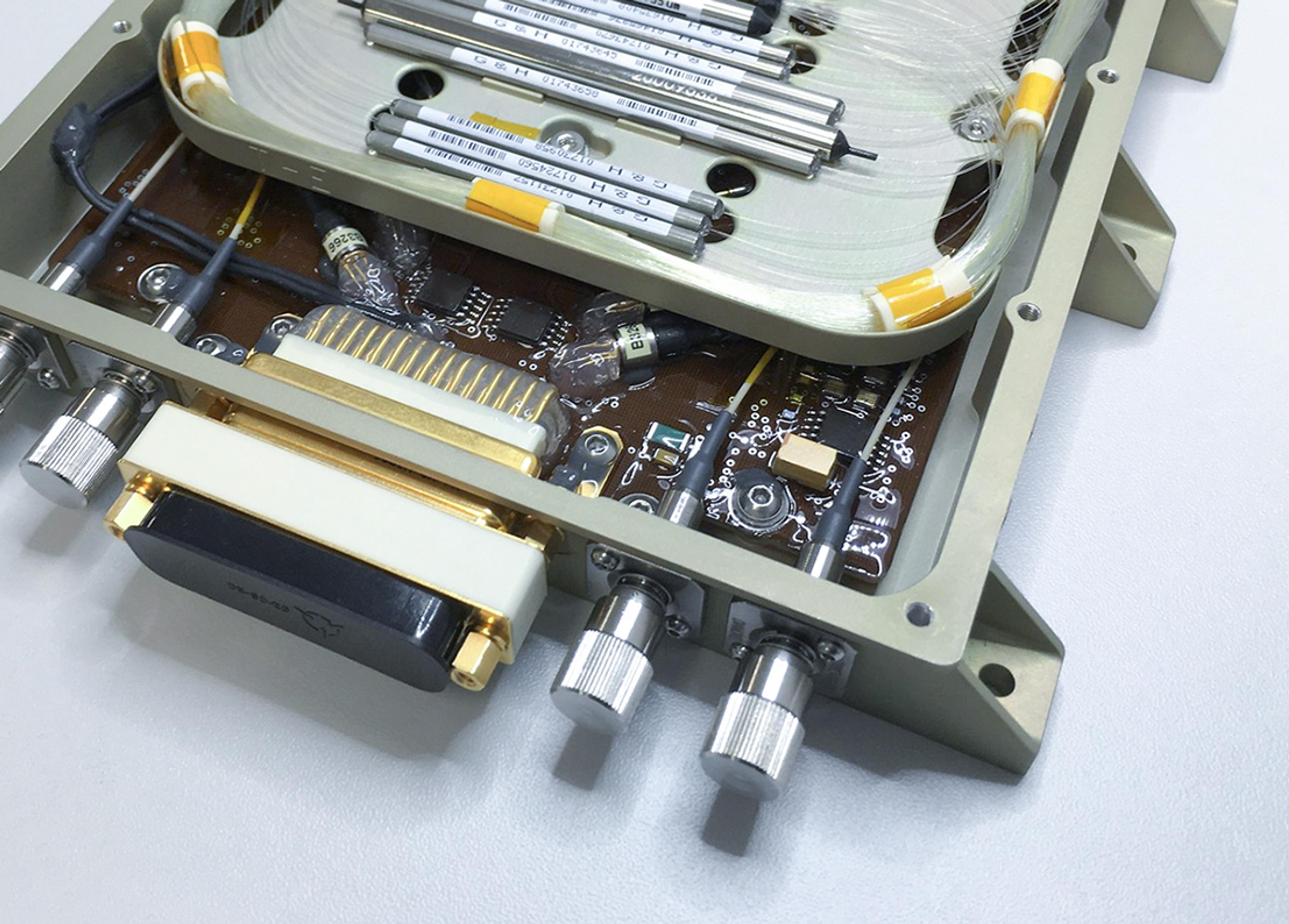 Internal view of a G&H custom OEM fiber optic module showing coiled optical fibers, precision components, electronic circuitry and multiple optical connectors within a rugged enclosure.