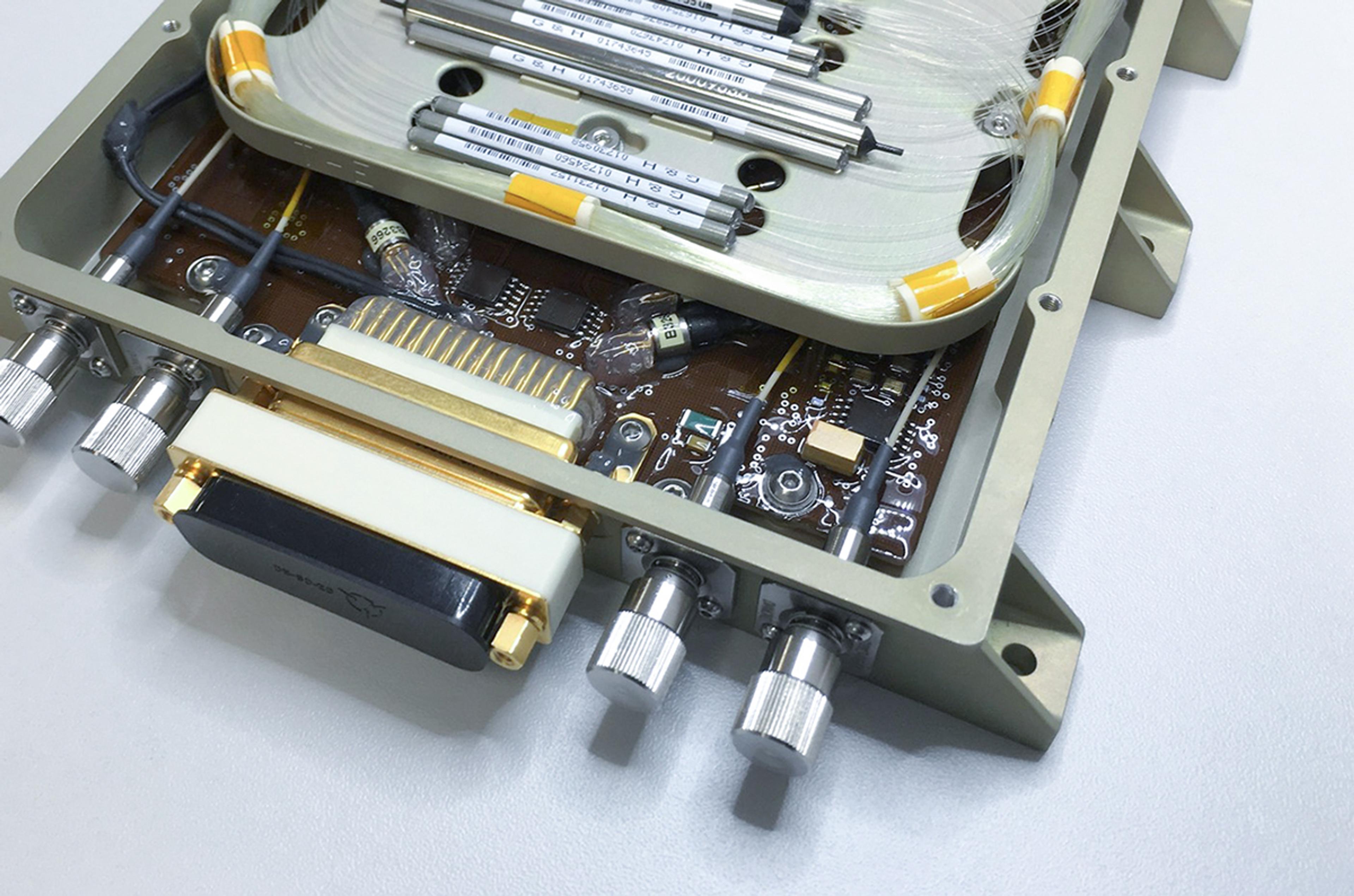 Internal view of a G&H custom OEM fiber optic module showing coiled optical fibers, precision components, electronic circuitry and multiple optical connectors within a rugged enclosure.