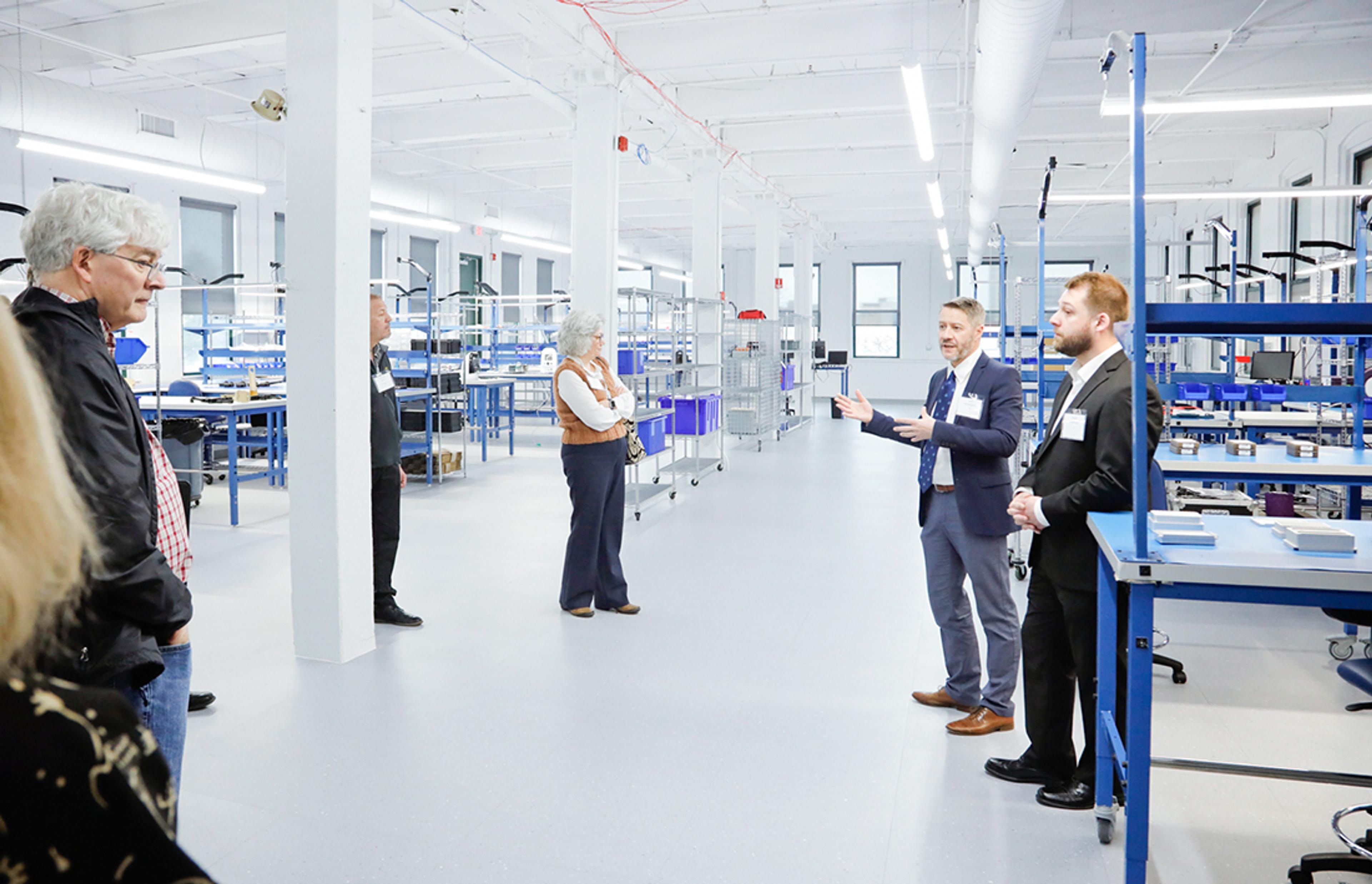 One of the tours during the Innovation Hub grand opening in Rochester.  A white open space with blue assembly tables and G&H life sciences consumables