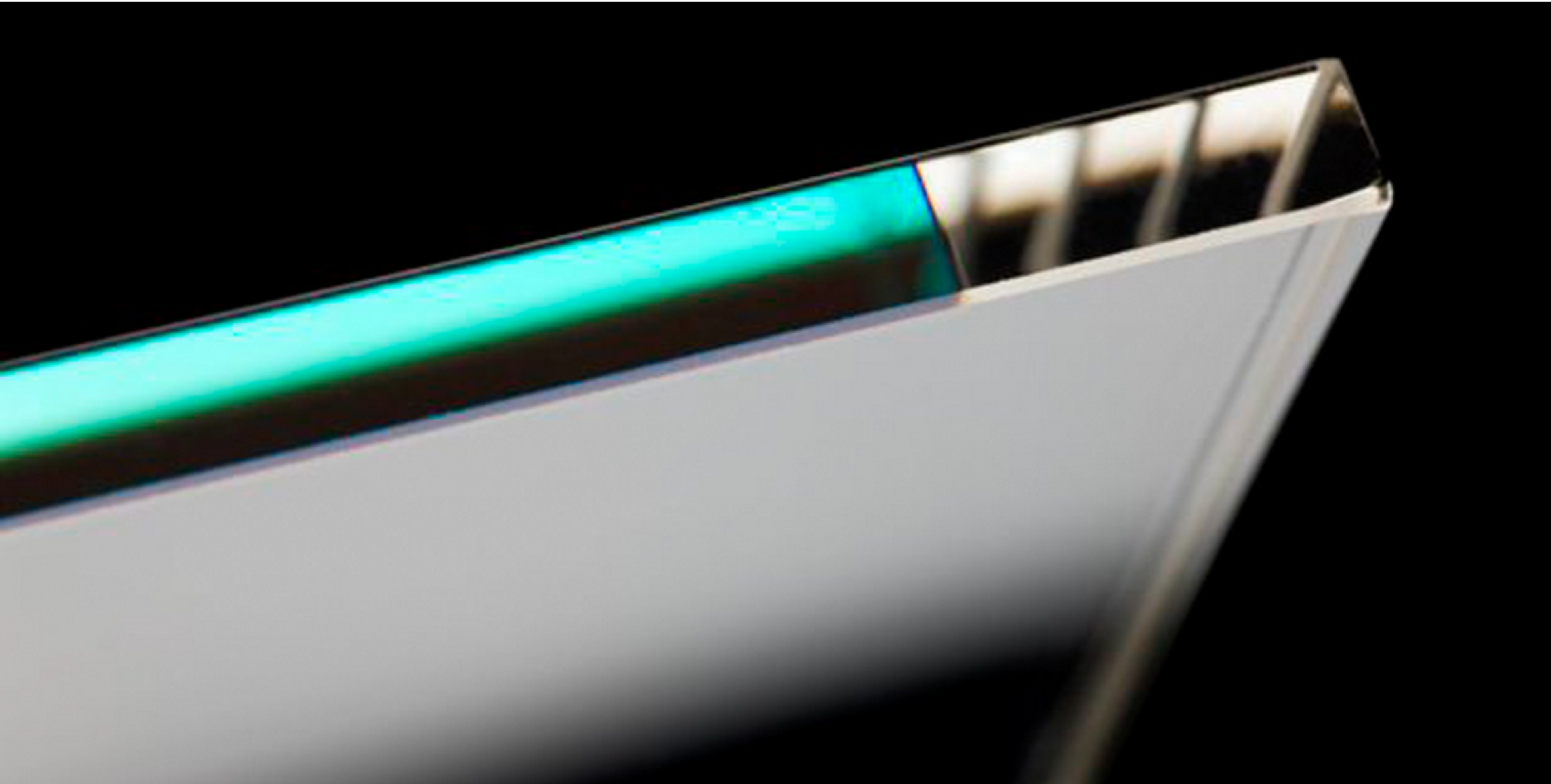 Close-up of the edge of a cemented optical assembly, showing the precise alignment of multiple transparent layers with a faint green reflection. The image highlights the clarity and bonding quality of the optical components against a dark background.