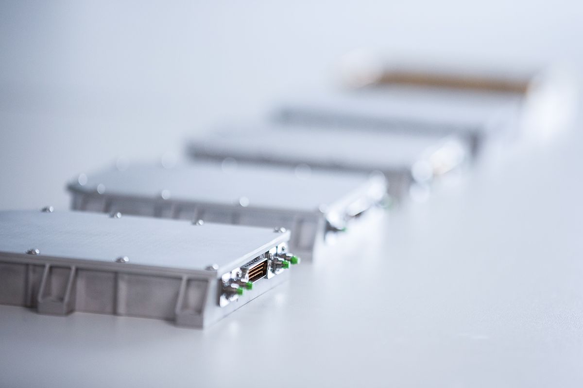 Close-up of G&H custom OEM fiber optic modules in compact metal housings, showing precision connectors and integrated optical components.