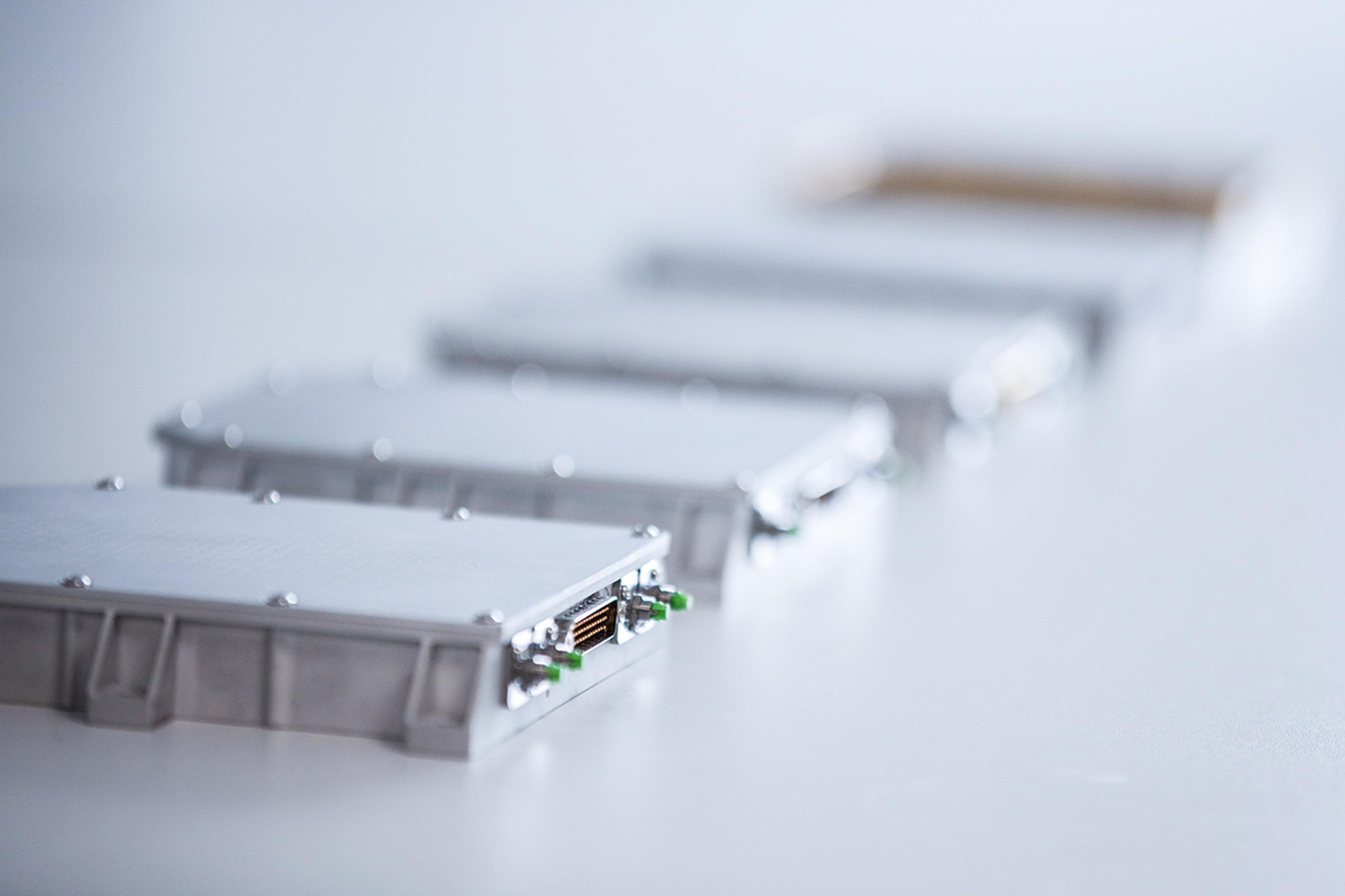 Close-up of G&H custom OEM fiber optic modules in compact metal housings, showing precision connectors and integrated optical components.
