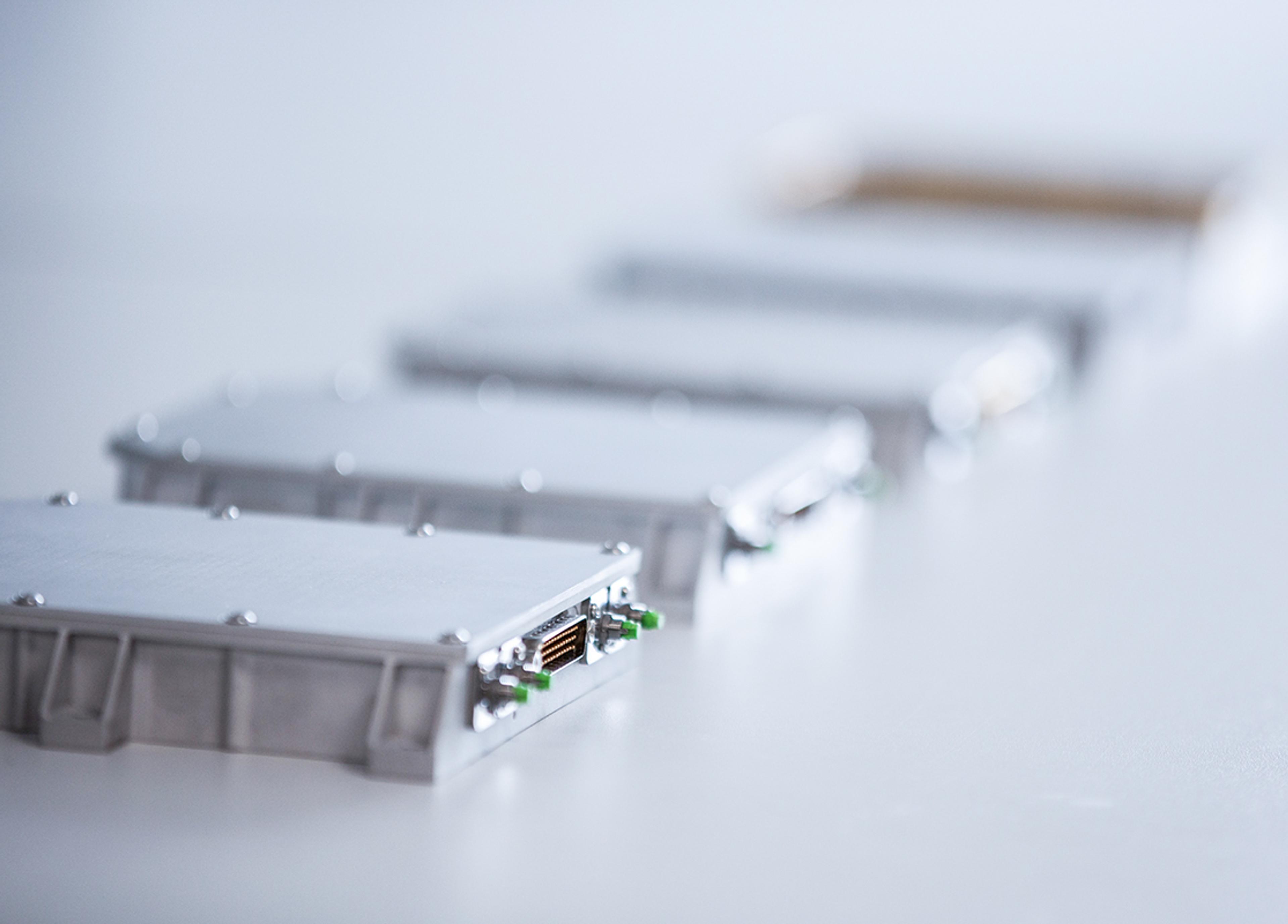 Close-up of G&H custom OEM fiber optic modules in compact metal housings, showing precision connectors and integrated optical components.