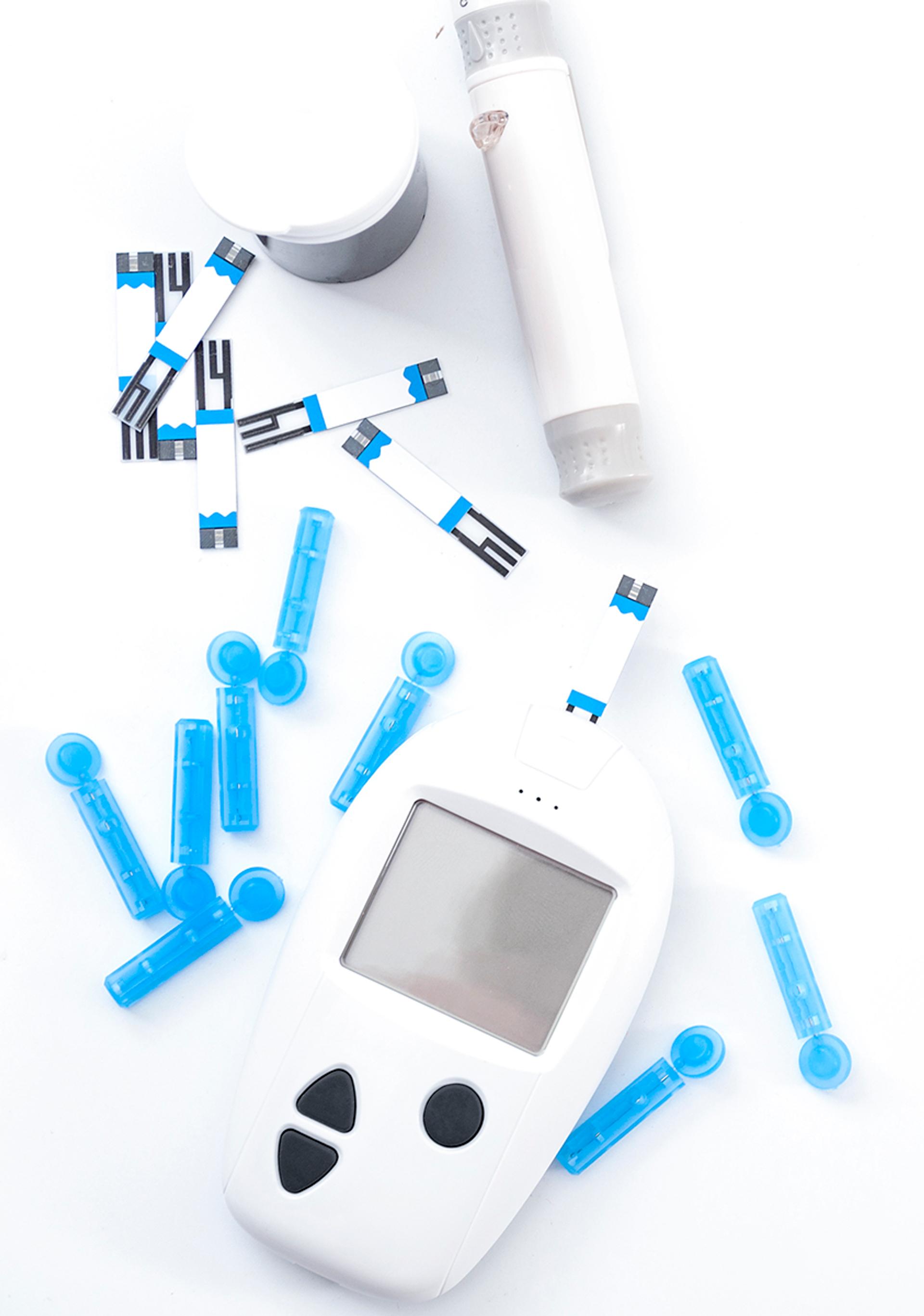 Blood glucose meter and lancing device with test strips and blue lancets on a white background.