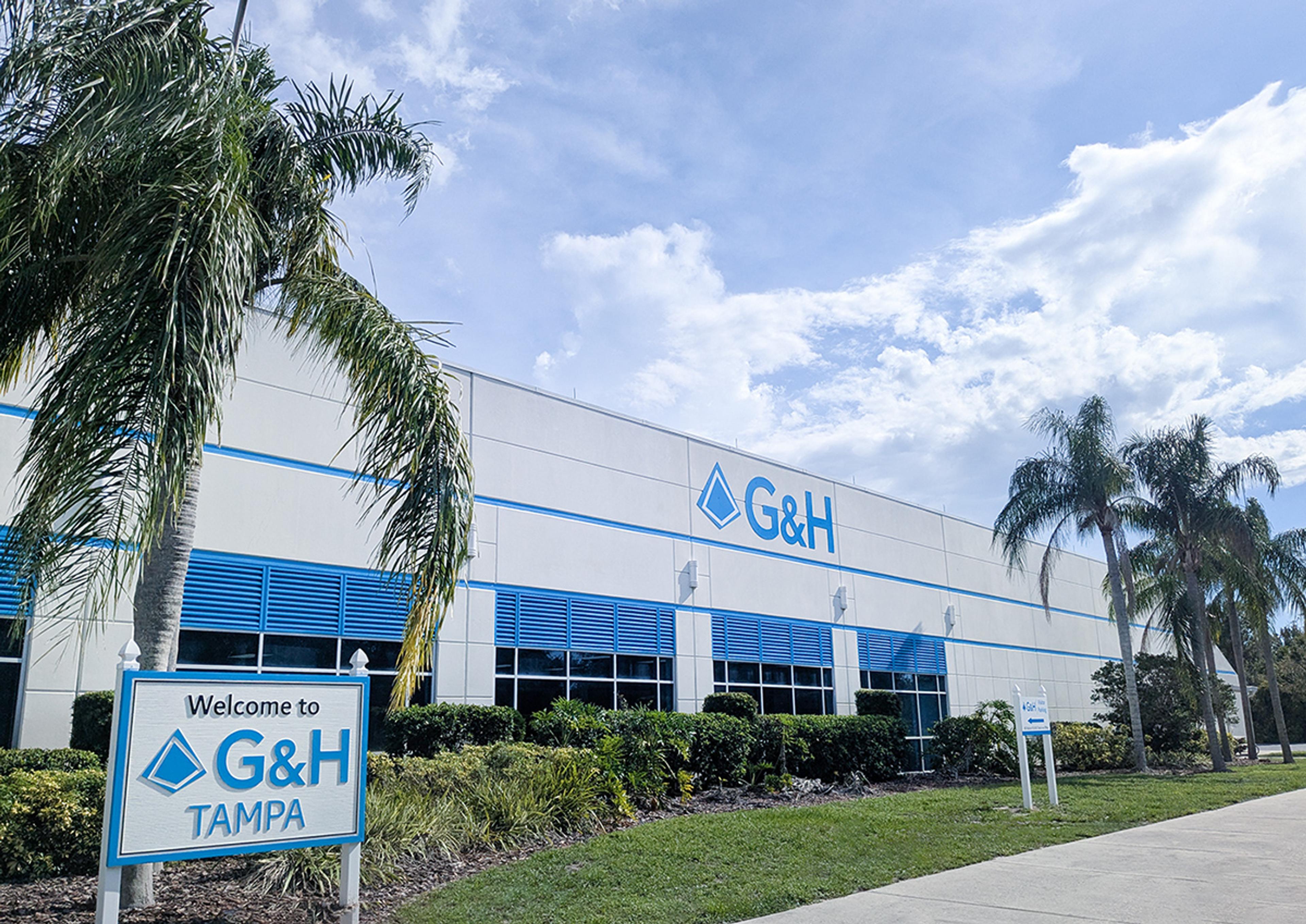 G&H Tampa facility exterior with palm trees, blue sky, and a welcome sign outside the building.