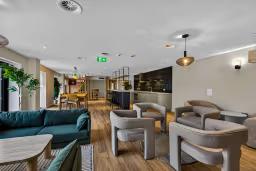 Bright communal lounge with armchairs, sofas, dining tables, and a modern kitchen area for studying and socialising.