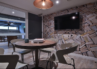 Modern study room with round tables, comfortable seating, a wall-mounted TV, and contemporary interior design.