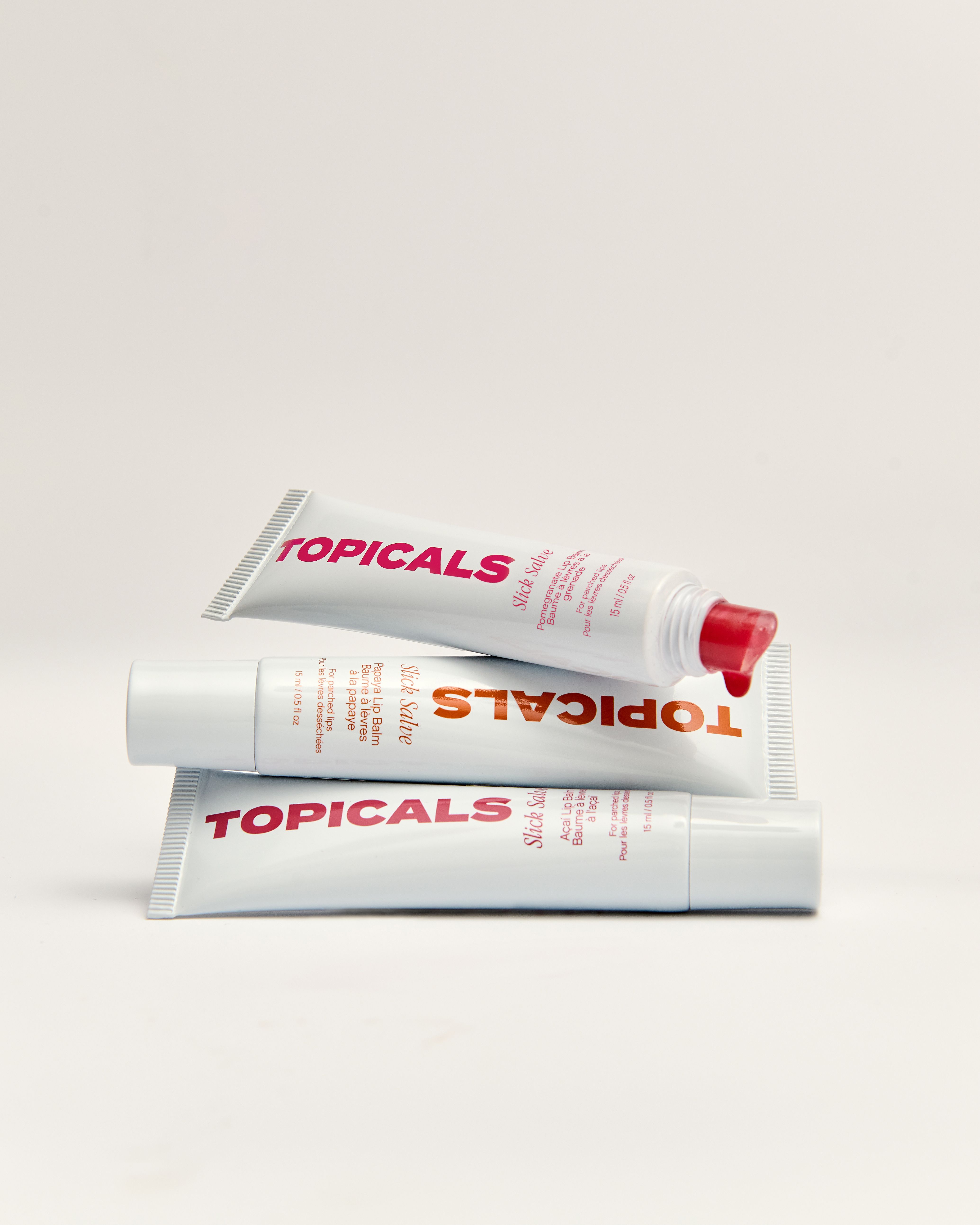 Three white tubes of TOPICALS Slick Salve, one with red product squeezed from its cap, stacked on a white background.