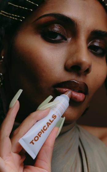 a woman is holding a tube of lip gloss in her hand .