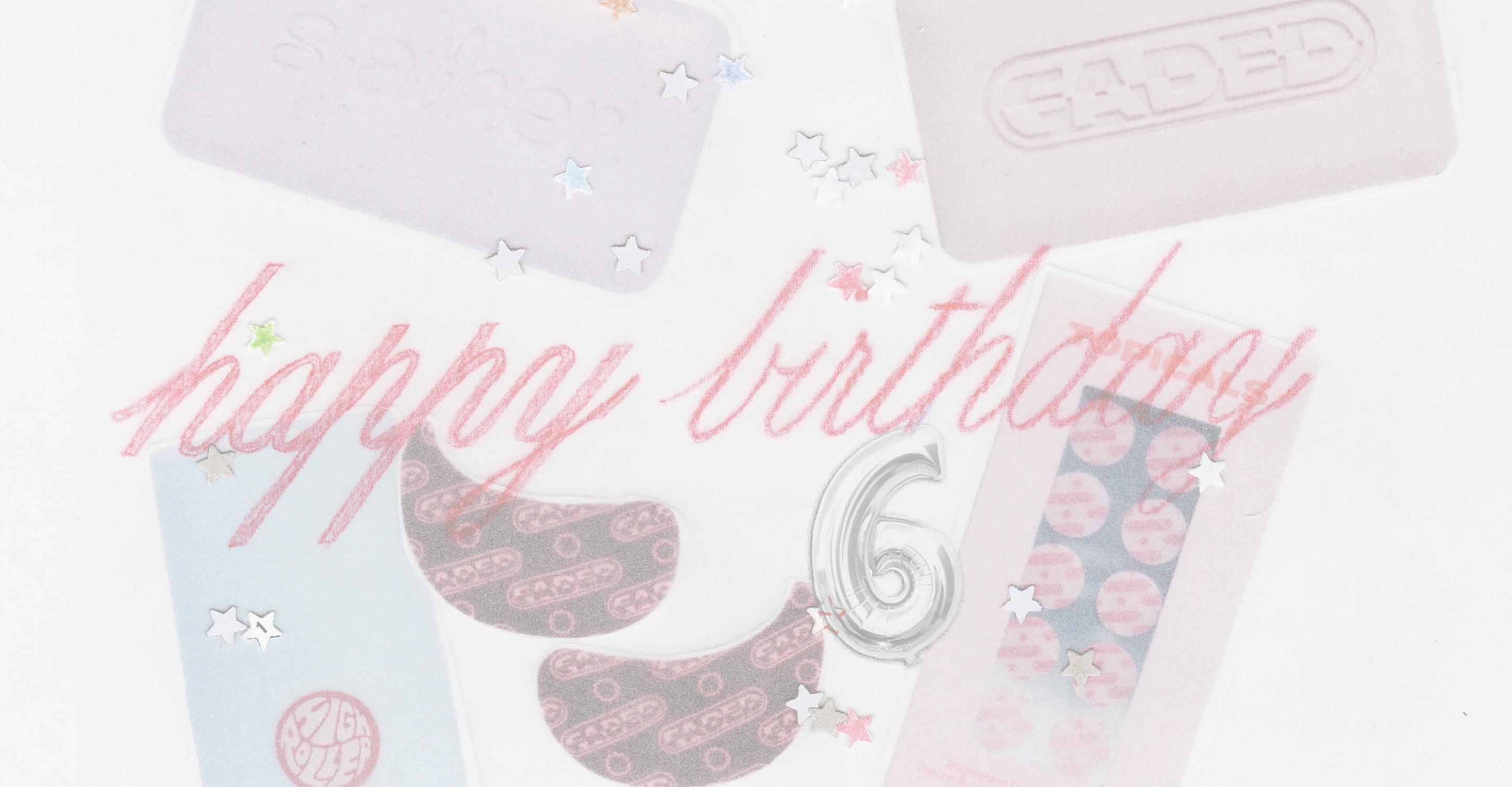 Flat lay of "Happy birthday" in red script with a number 6 balloon, pink bars, eye masks, and star confetti on a white surface.
