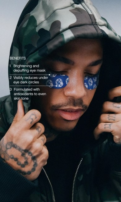 A man in a camouflage hoodie wearing blue eye masks patterned with astronaut helmets, with text listing eye mask benefits.