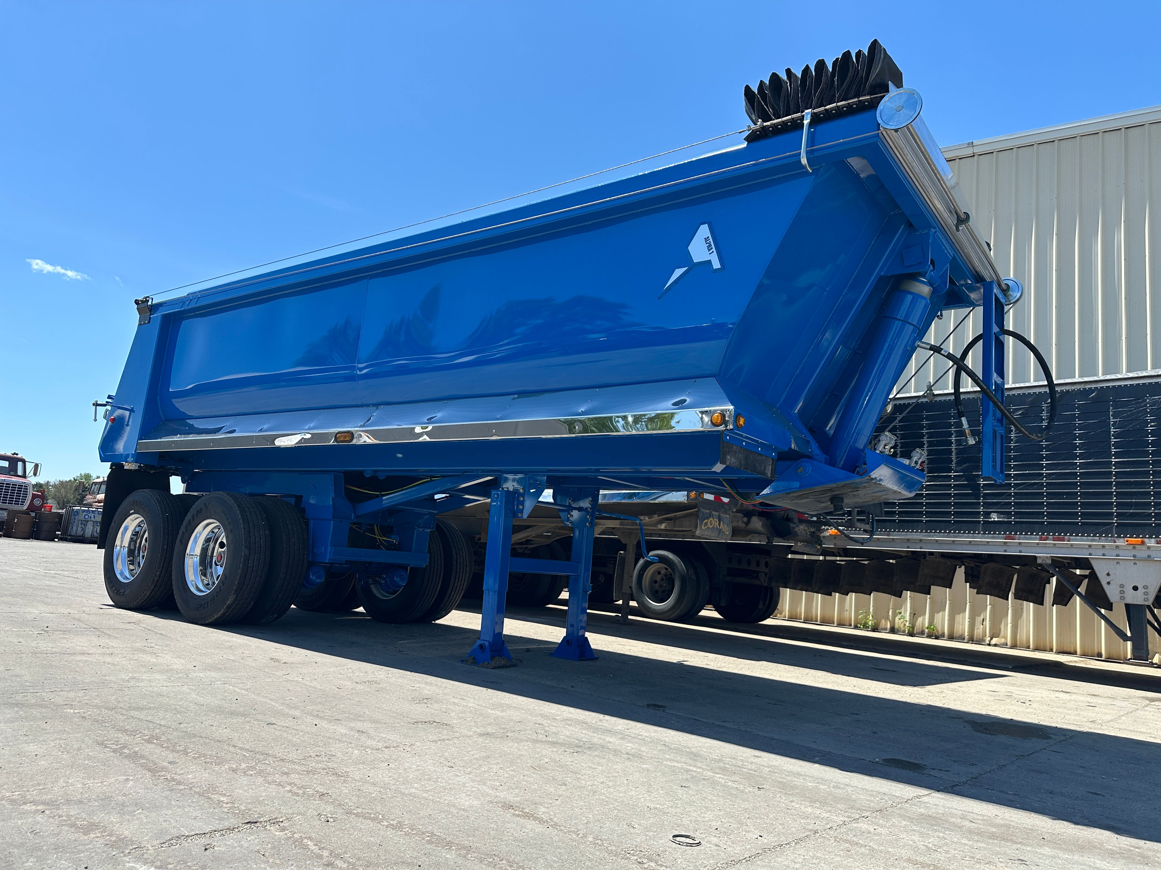 Purple truck pulling on a black dump trailer