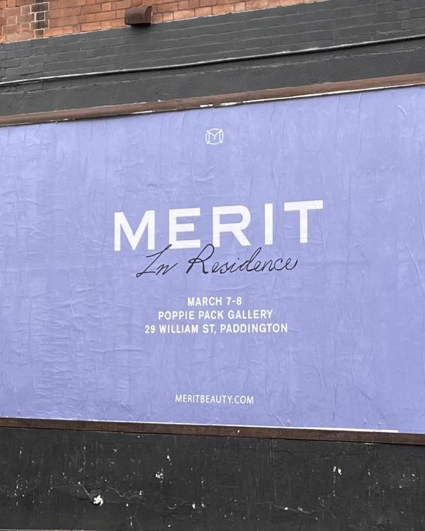 The lilac MERIT In Residence poster pasted across a street wall in Sydney