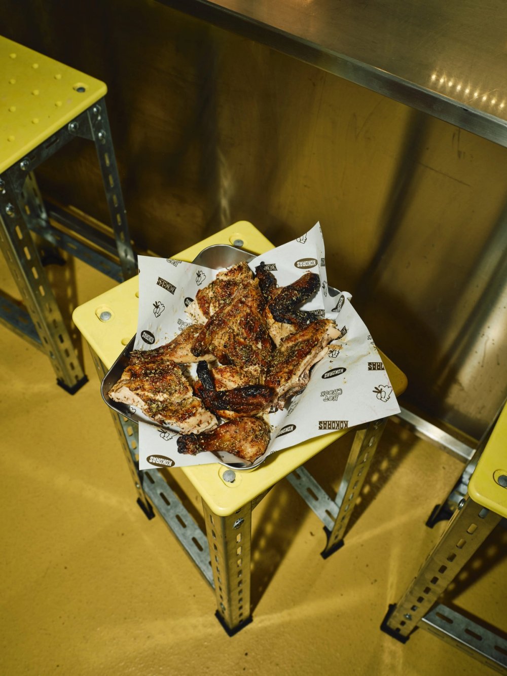 Chicken on Kokoras paper on a yellow stool