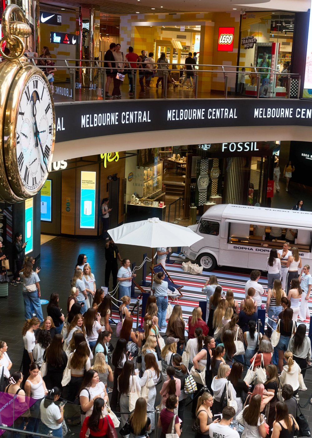 The crowd under the clock at Melbourne Central, the van and striped stage behind