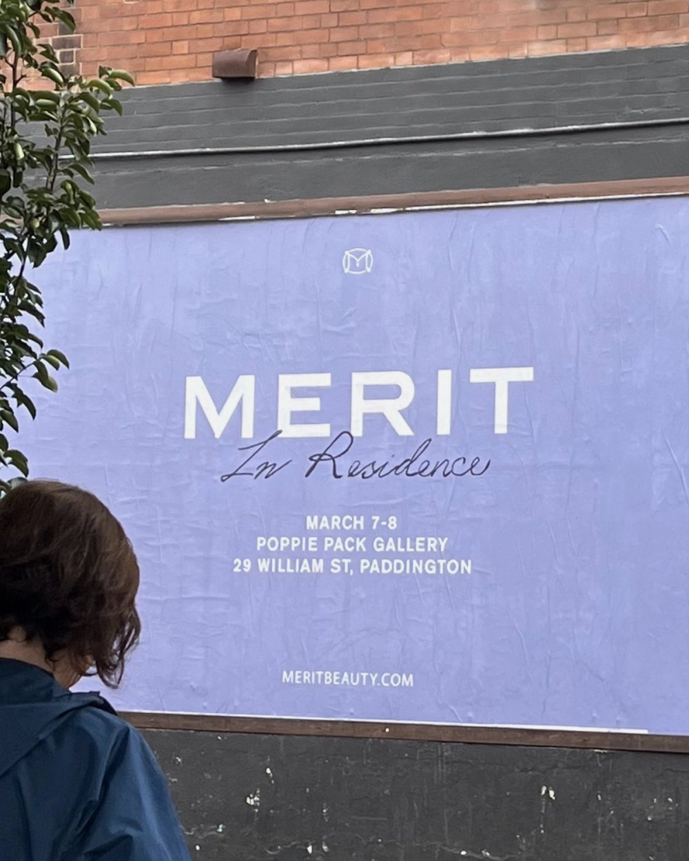Someone walking past the MERIT In Residence poster on the street