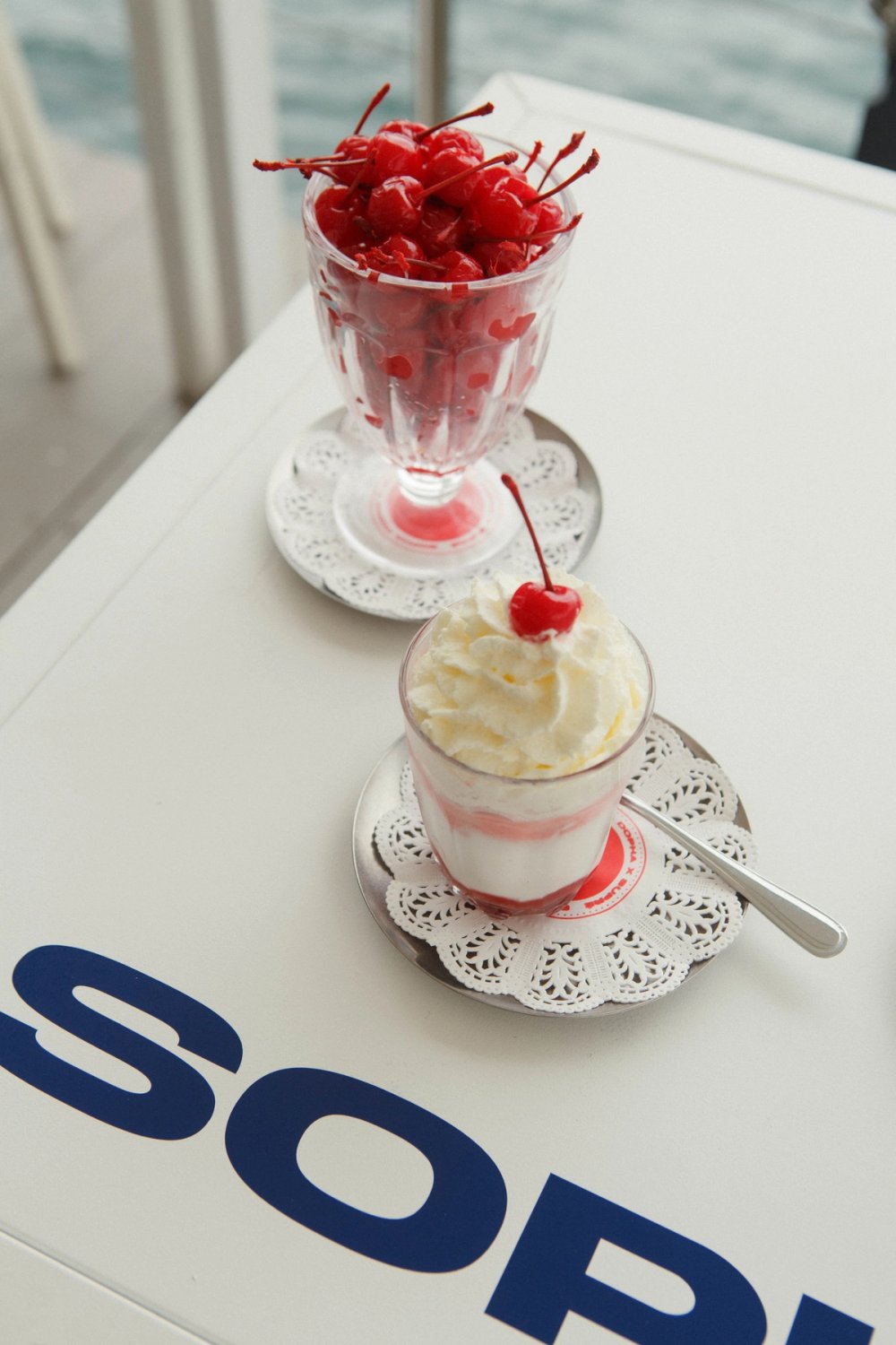 Sundaes on stamped doilies and a glass of cherries on a branded table