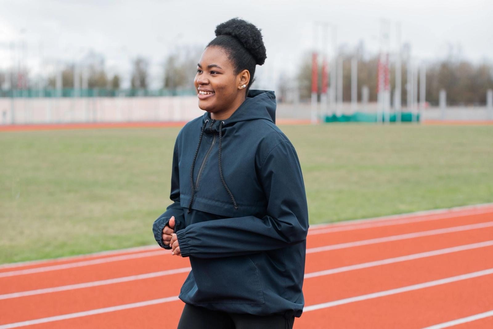 A woman jogging on an outdoor running track.
