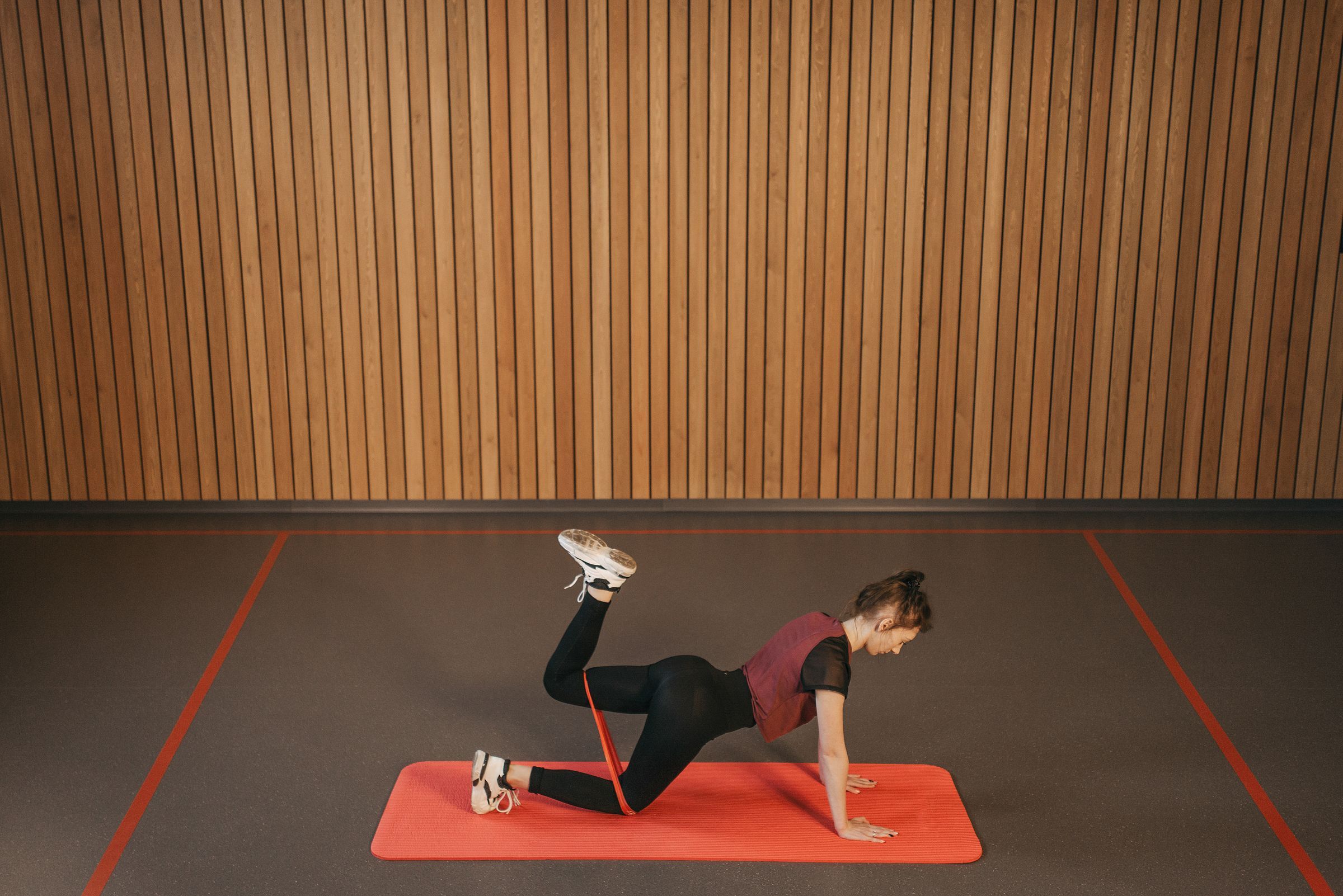 A woman exercising with a resistance band on a mat.