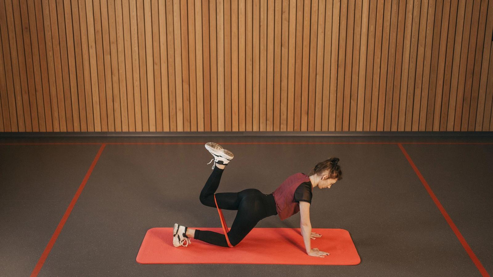 A woman exercising with a resistance band on a mat.