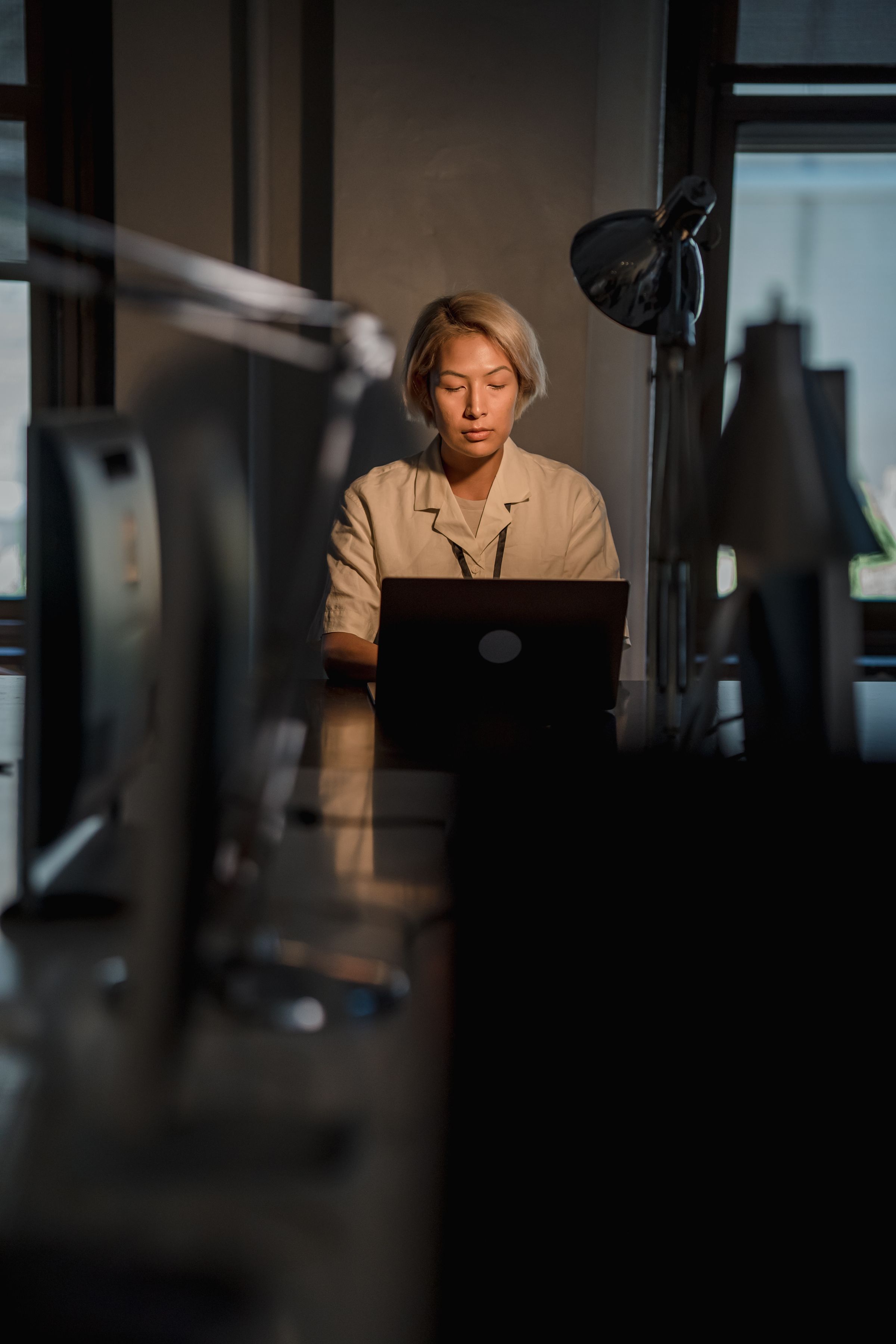 A woman working at a desk in an office at night.